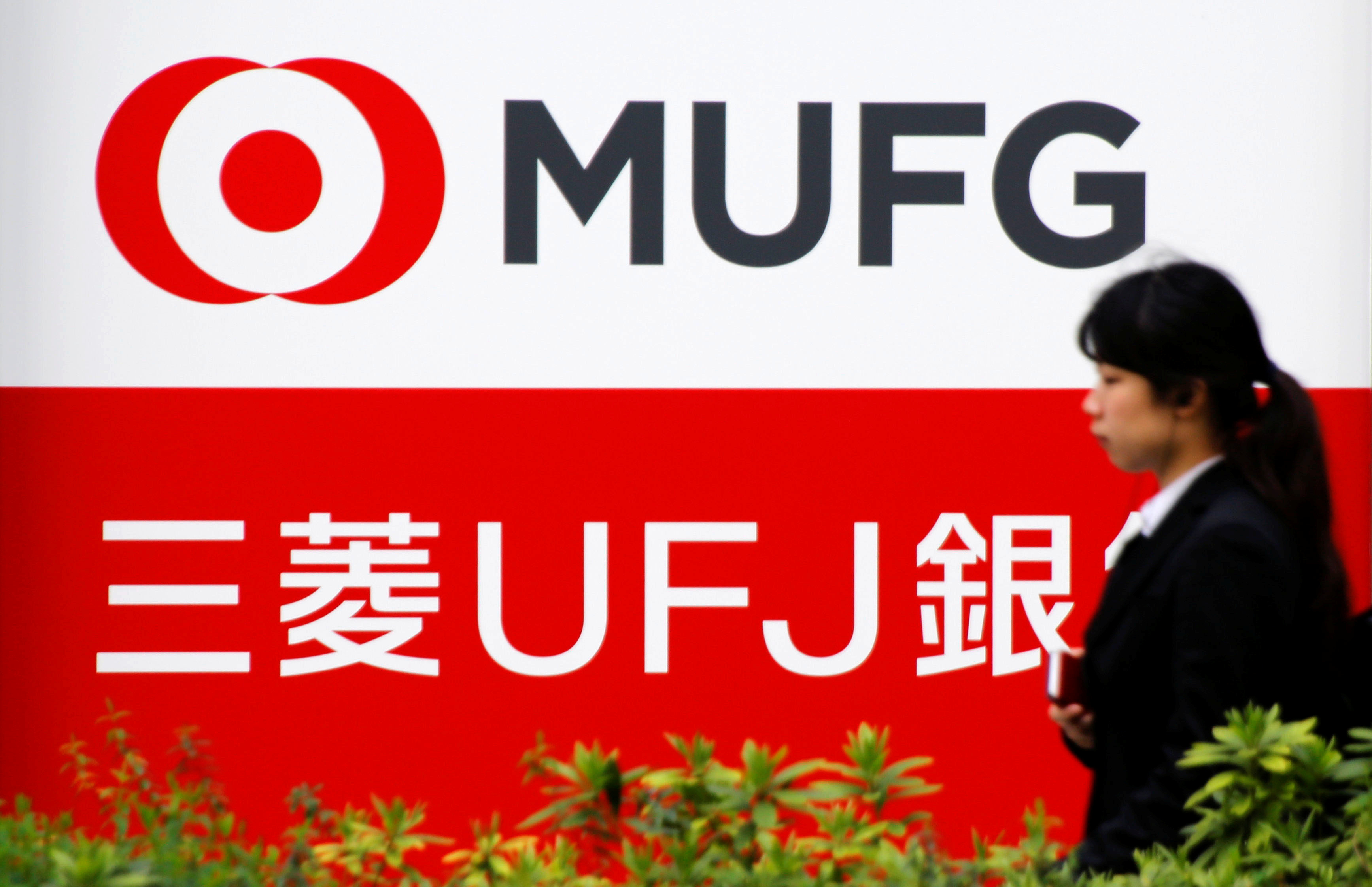 A woman walks past a signboard of MUFG Bank in Tokyo