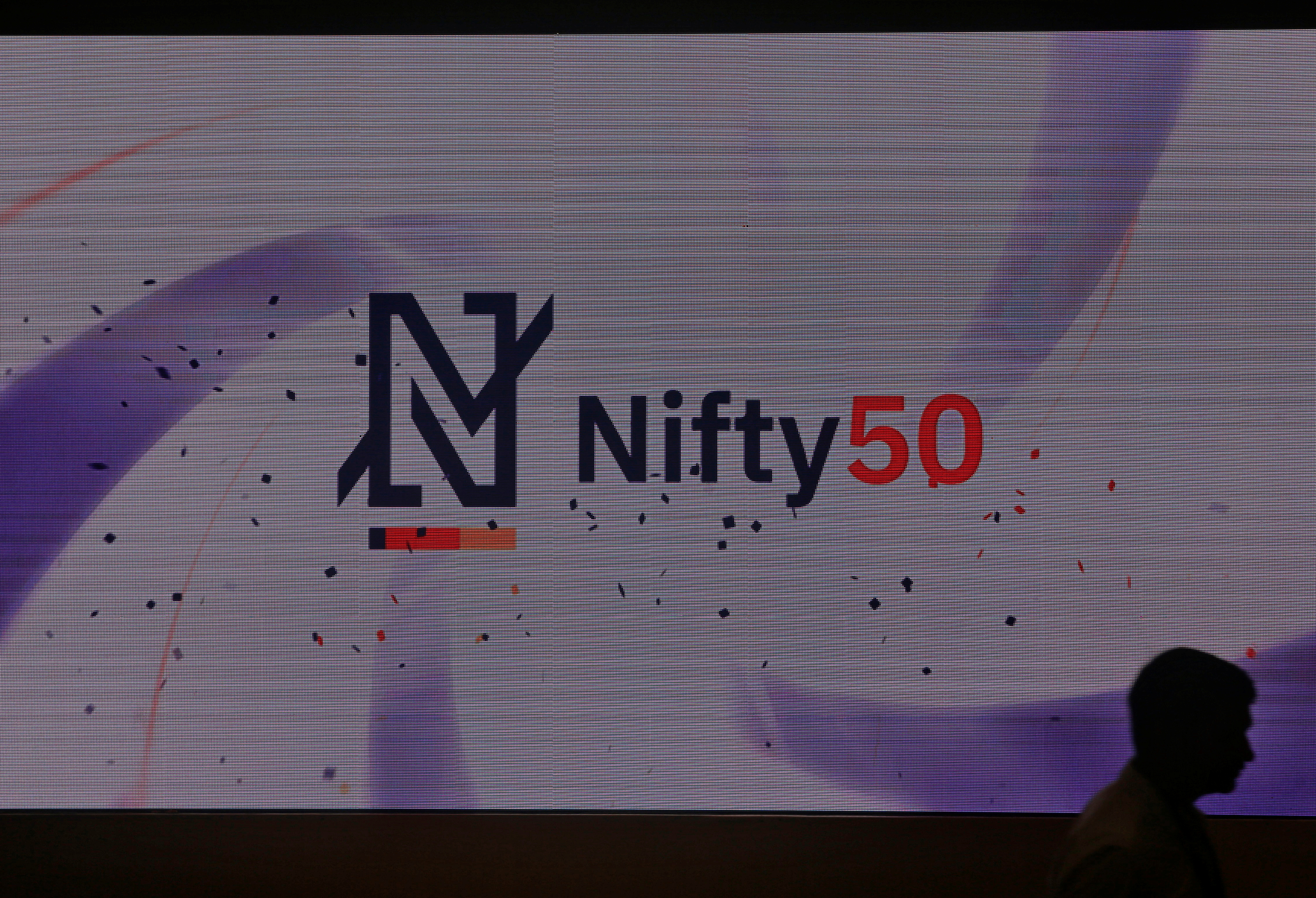 A man walks past a newly launched Nifty Indices logo inside the National Stock Exchange building in Mumbai