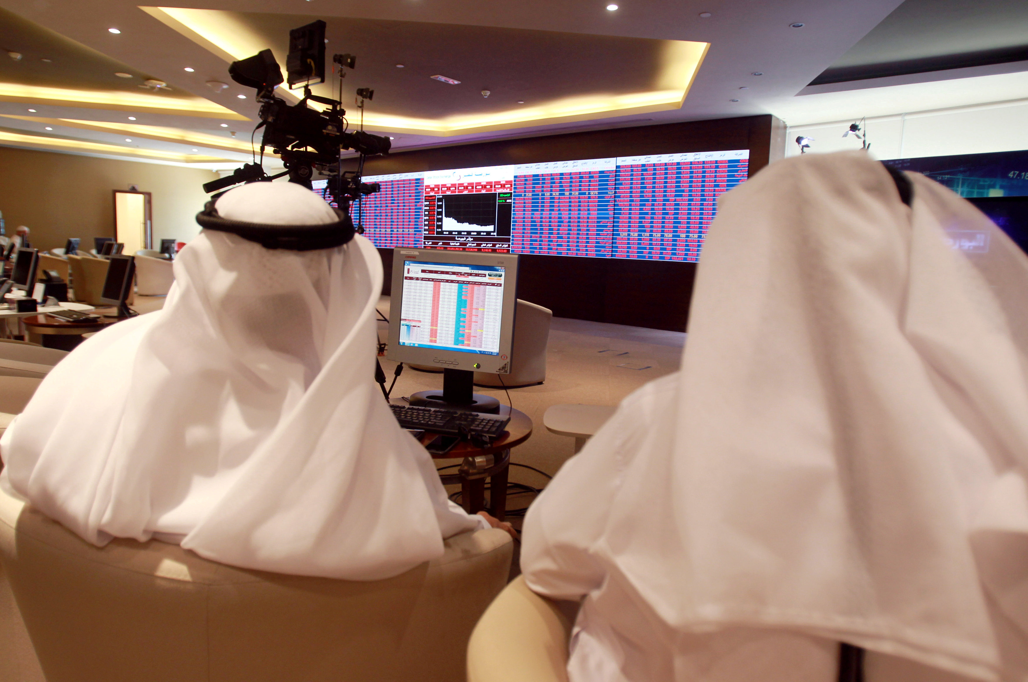 Traders monitor screens displaying stock information at Qatar Stock Exchange in Doha