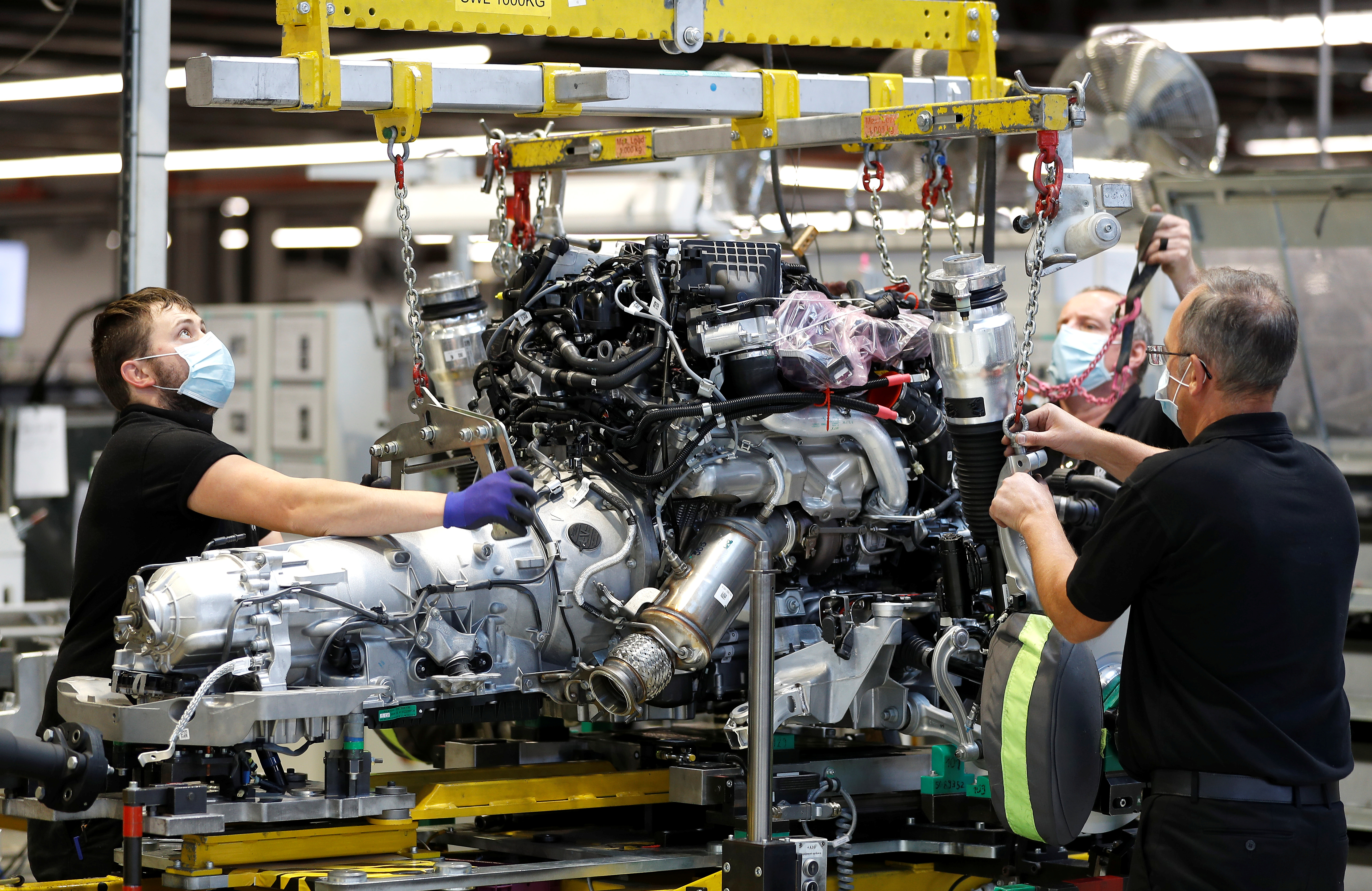 Technicians work on a Rolls-Royce engine prior to it being installed in a car on the production line of the Rolls-Royce Goodwood factory, near Chichester