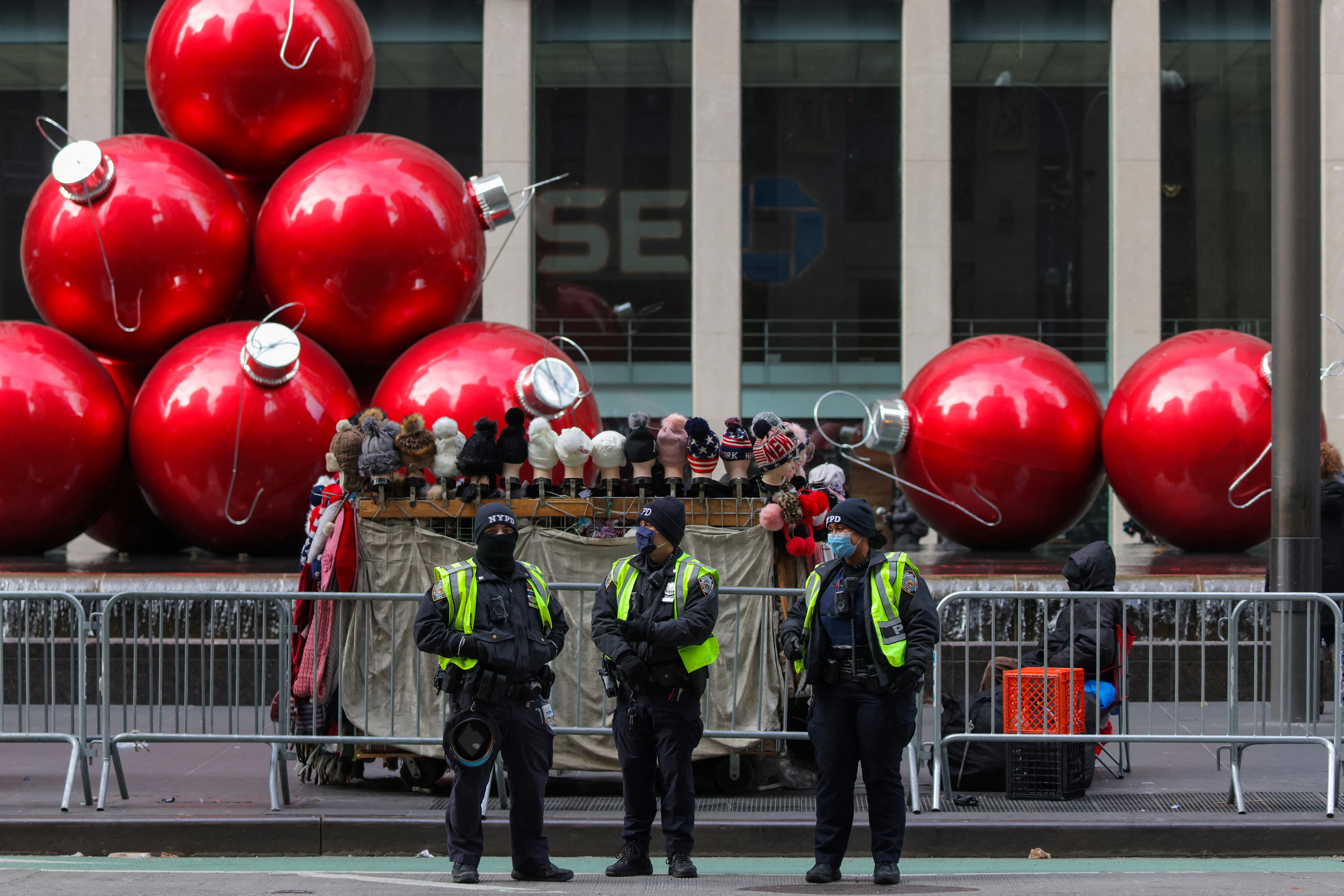 Members of the New York City Police Department (NYPD) wear face masks as they stand in front of holiday decorations on Sixth Avenue as the Omicron coronavirus variant continues to spread in Manhattan, New York City, U.S., December 19, 2021. REUTERS/Andrew Kelly
