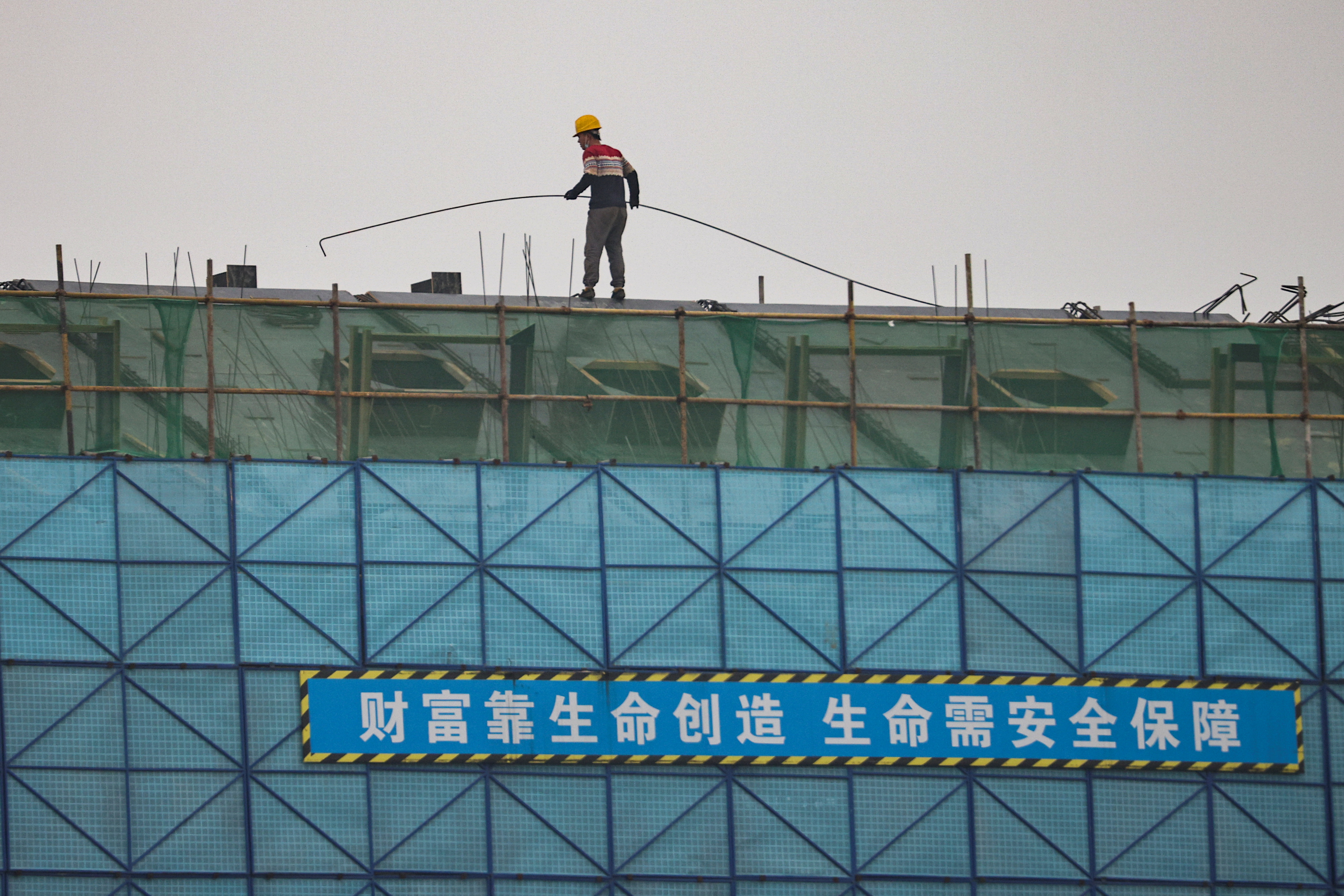 A man walks on a scaffolding at the construction site of the Beijing Xishan Palace apartment complex developed by Kaisa Group Holdings Ltd in Beijing, China, November 5, 2021.  REUTERS/Thomas Peter
