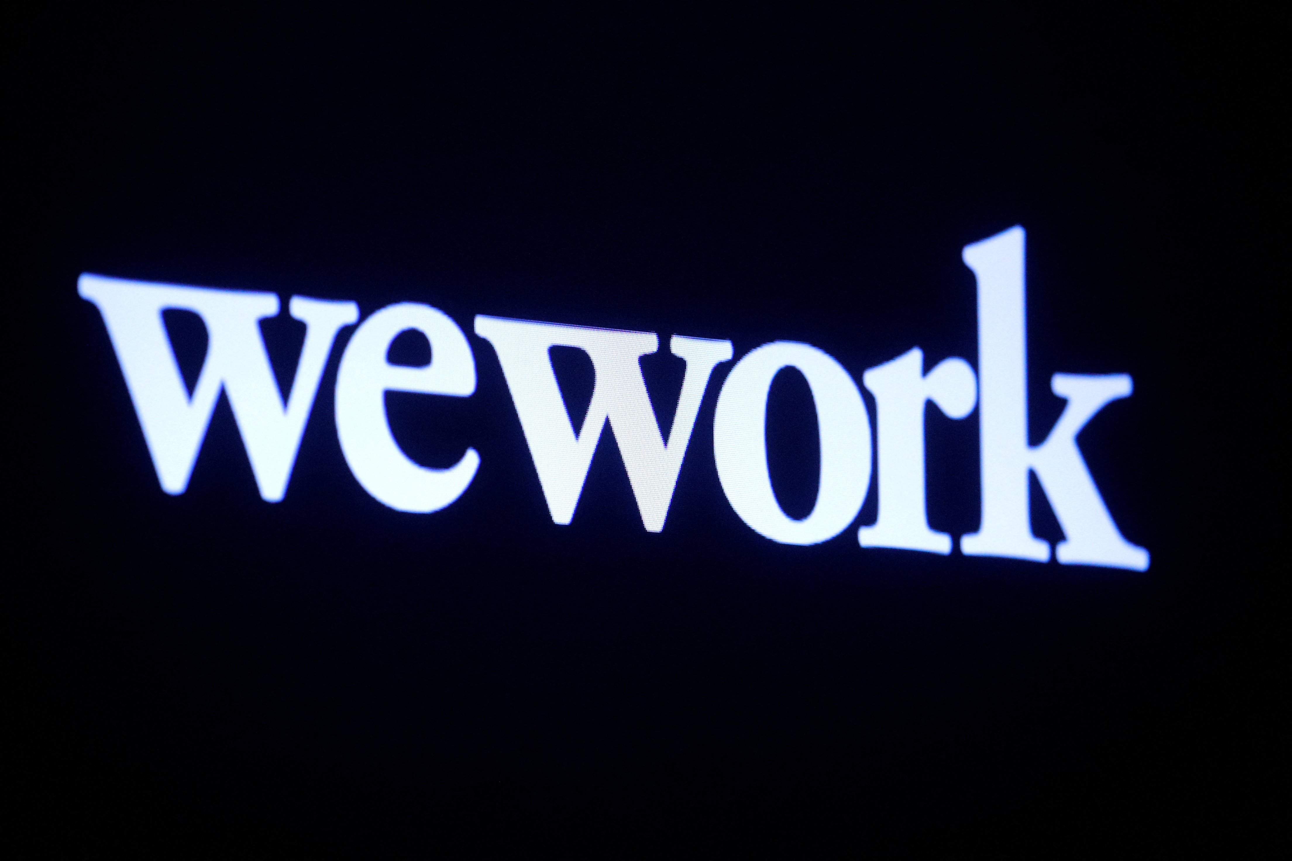 The WeWork logo is displayed on a screen during the company's IPO on the floor of the NYSE in New York
