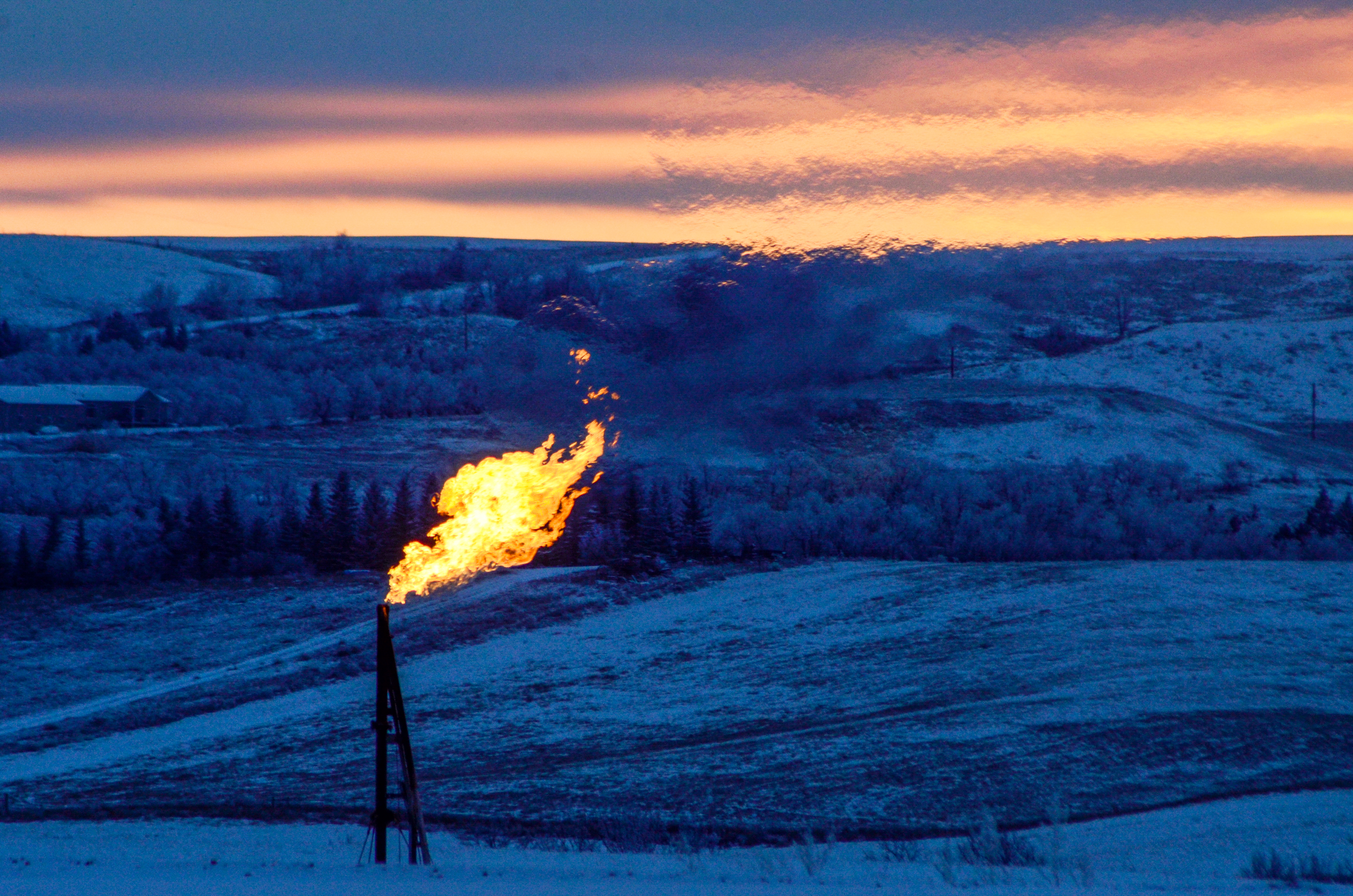 A natural gas flare on an oil well pad burns as the sun sets outside Watford City, North Dakota January 21, 2016. REUTERS/Andrew Cullen