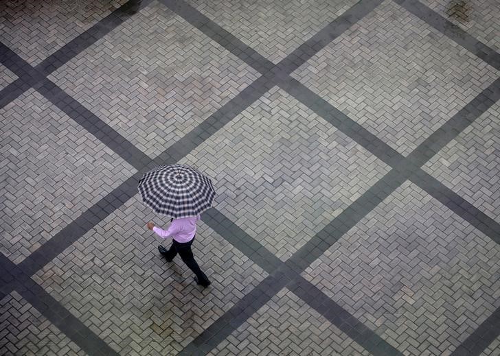 Office worker holding an umbrella walks out of a commercial building as it rains in Mumbai's central financial district