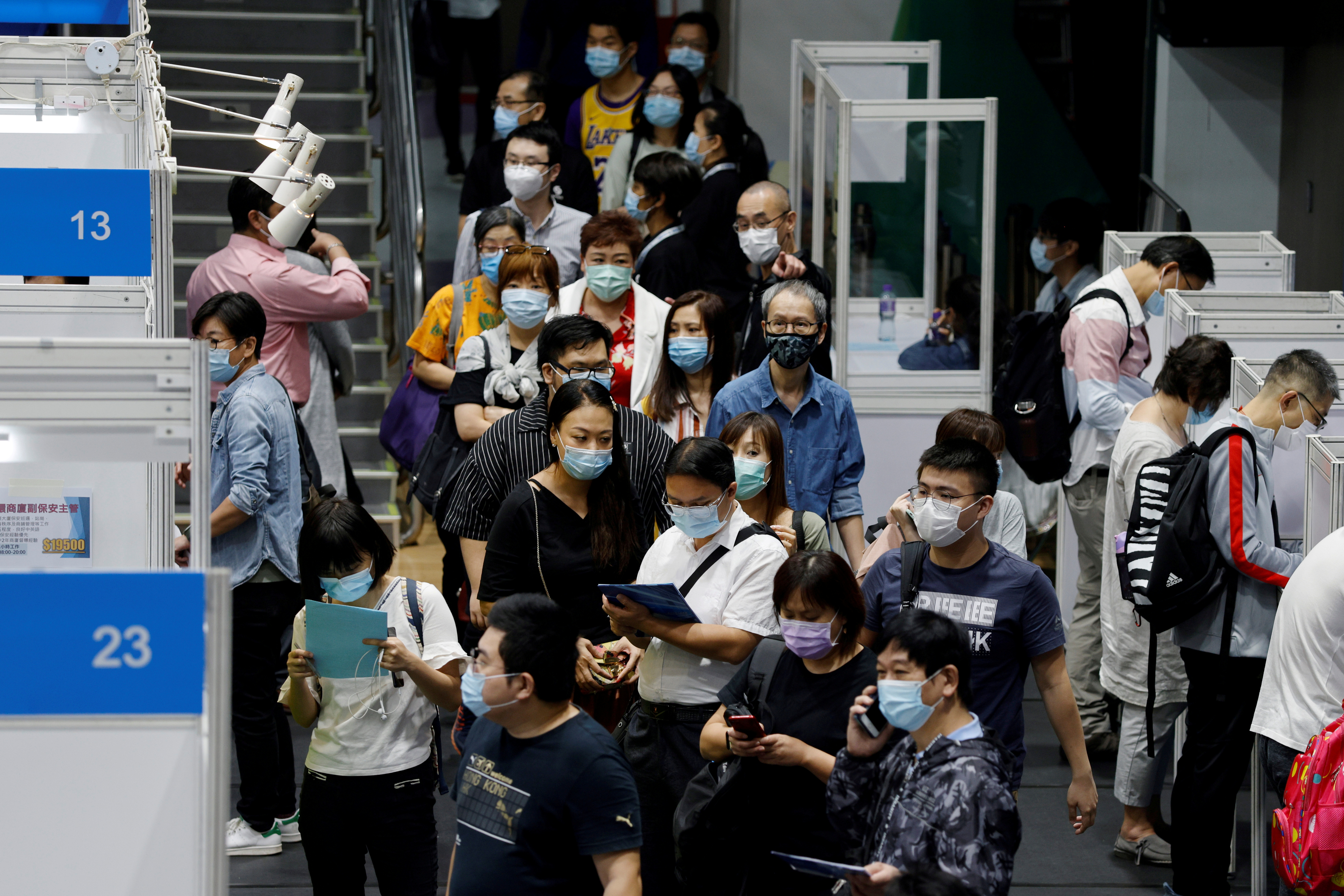 Job seekers wearing face masks fill in forms at a job fair in Hong Kong