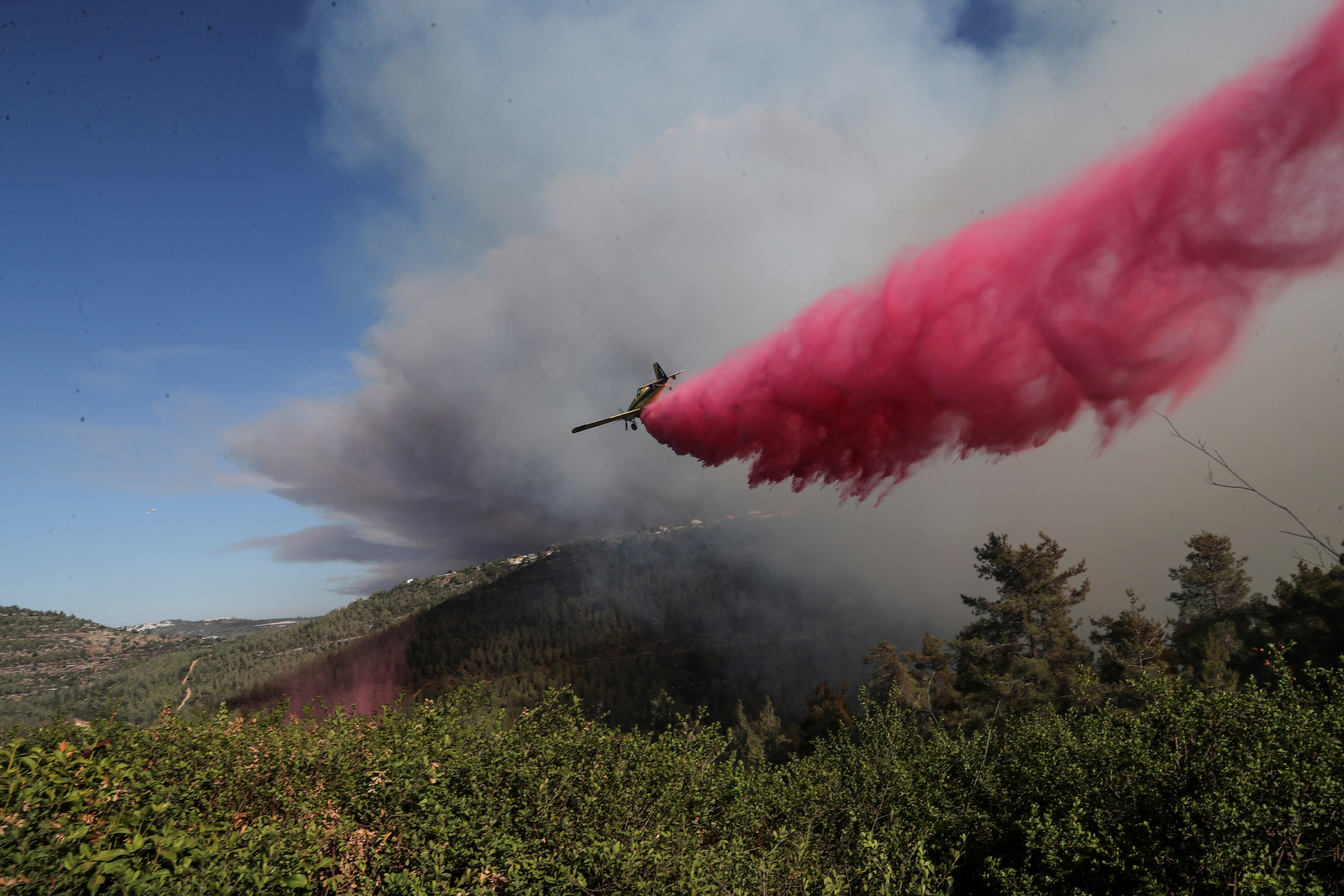 A firefighting plane disperses fire retardant as it assists in extinguishing a fire near the Israeli village of Shoresh at the outskirts of Jerusalem August 15, 2021. REUTERS/Ronen Zvulun