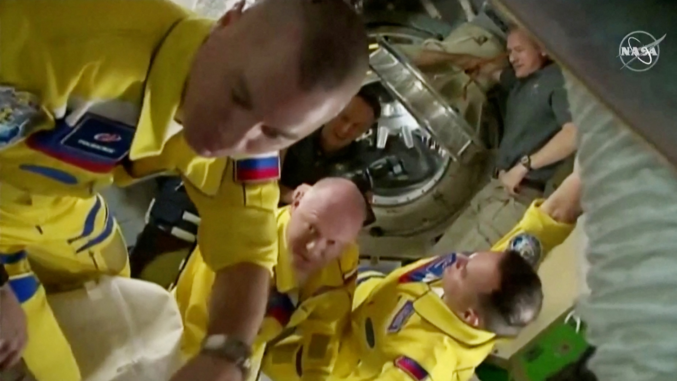 Russian cosmonauts arrive wearing yellow and blue flight suits at the International Space Station