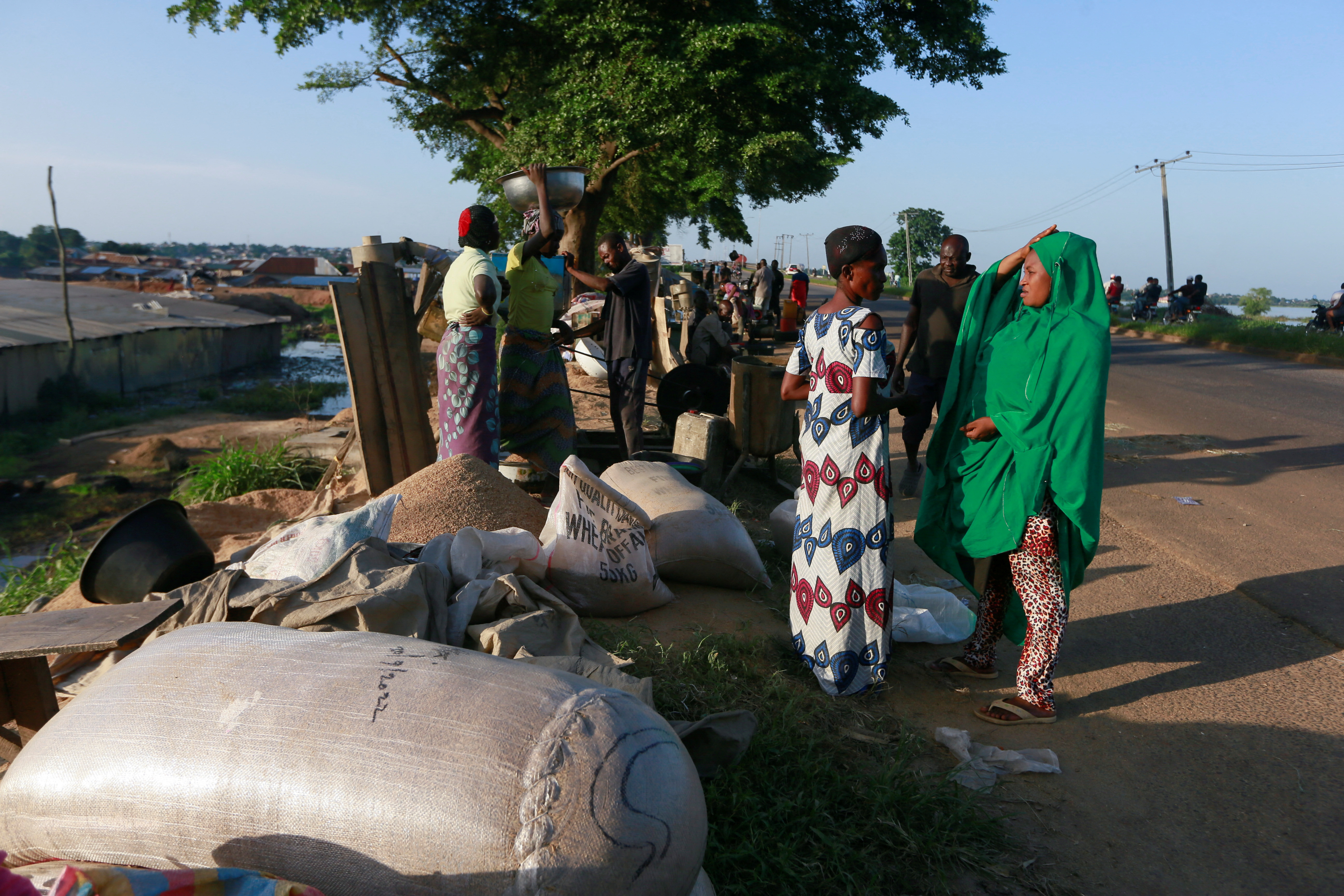 People gather around a rice milling machine beside the Wuruku rice mill market after a flood displaced millers from the market in Makurdi