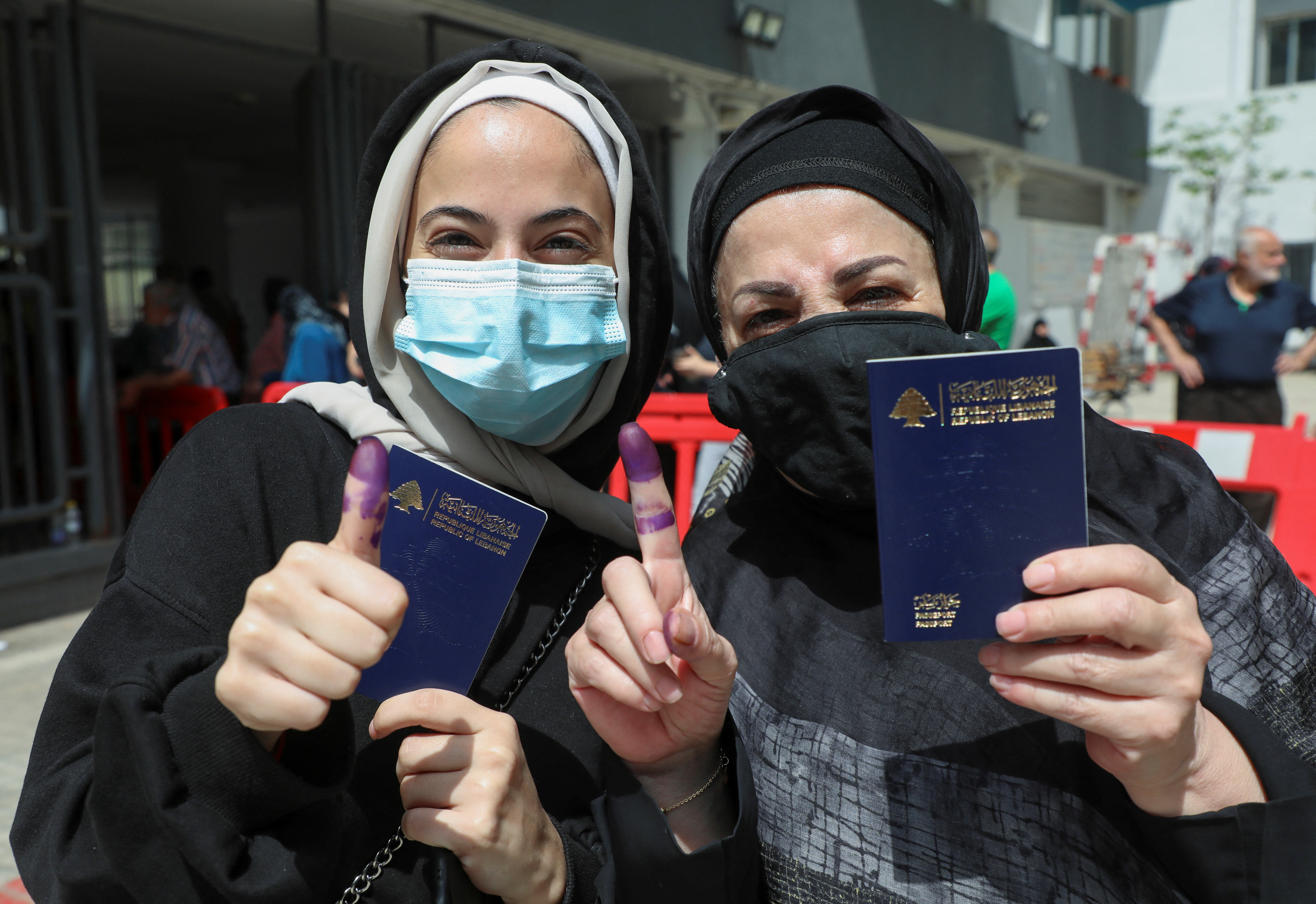 Women pose as they hold their Lebanese passports and show their ink-stained fingers after casting their vote in Lebanon's parliamentary election, in Beirut