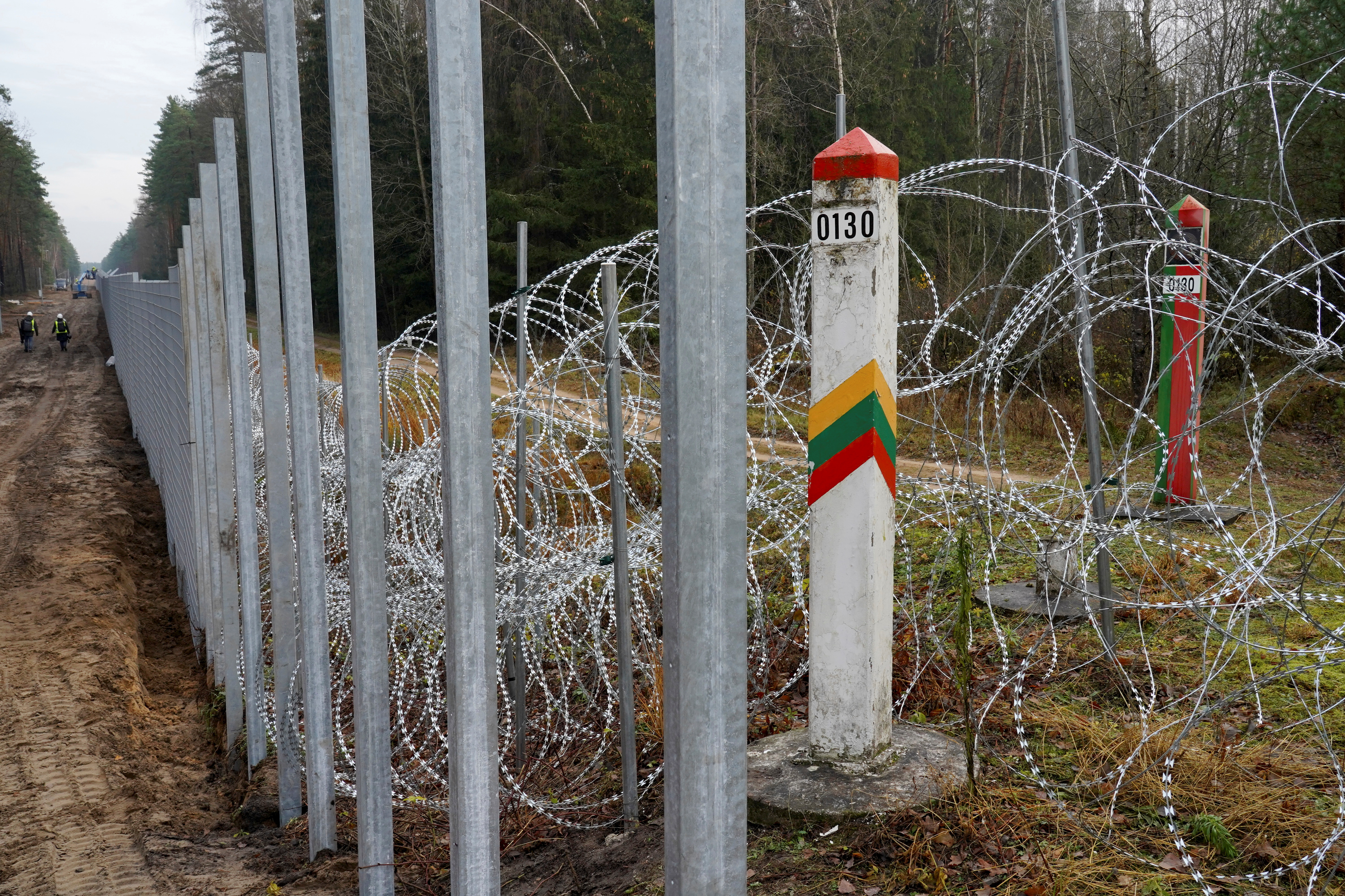 Belarusian and Lithuanian border mark poles are seen near a four-meter-high fence on the Belarusian border in Druskininkai, Lithuania November 4, 2021. REUTERS/Janis Laizans