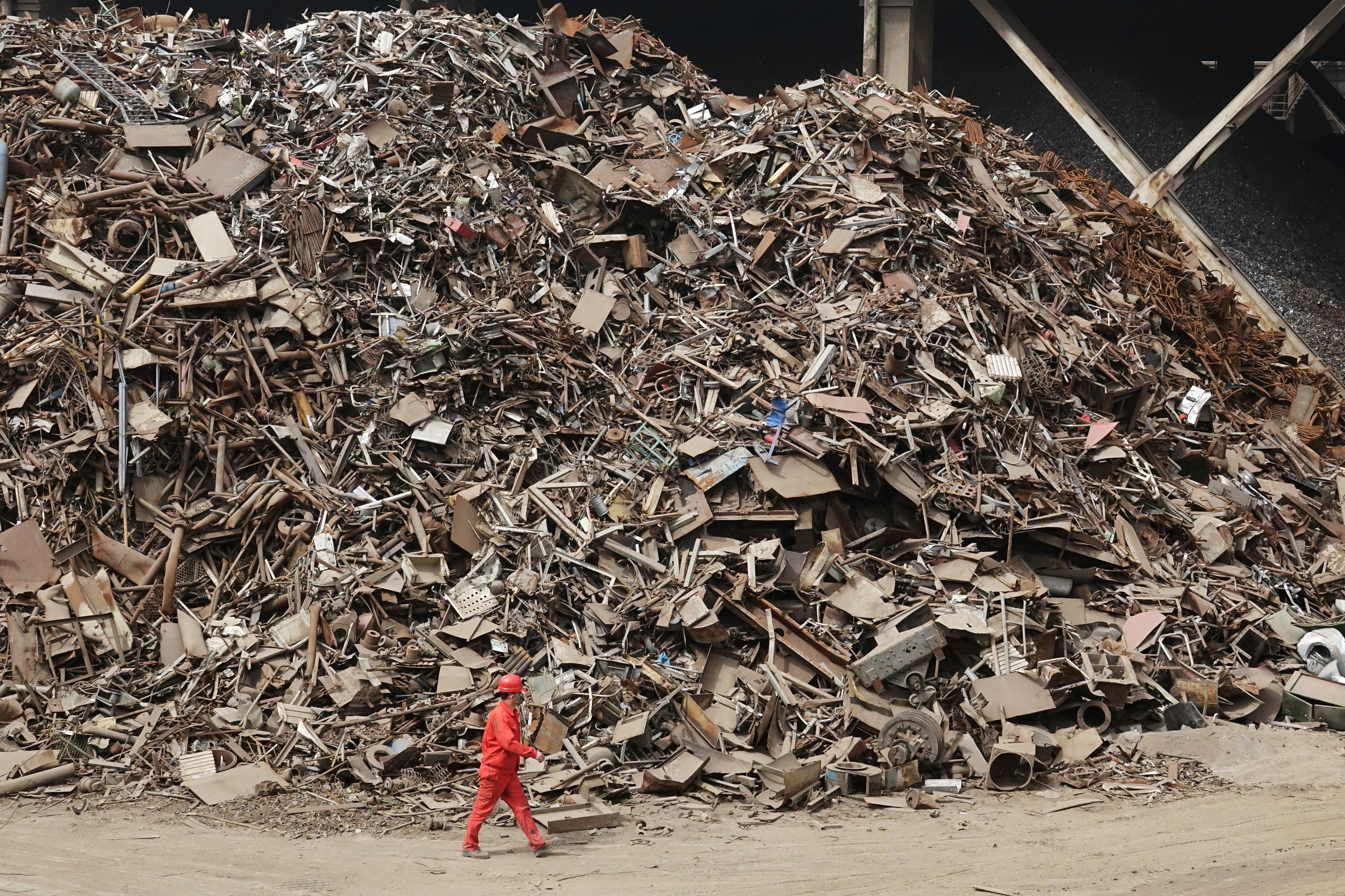 Worker walks past piles of scrap steel at a plant of Dongbei Special Steel Group Co Ltd in Dalian