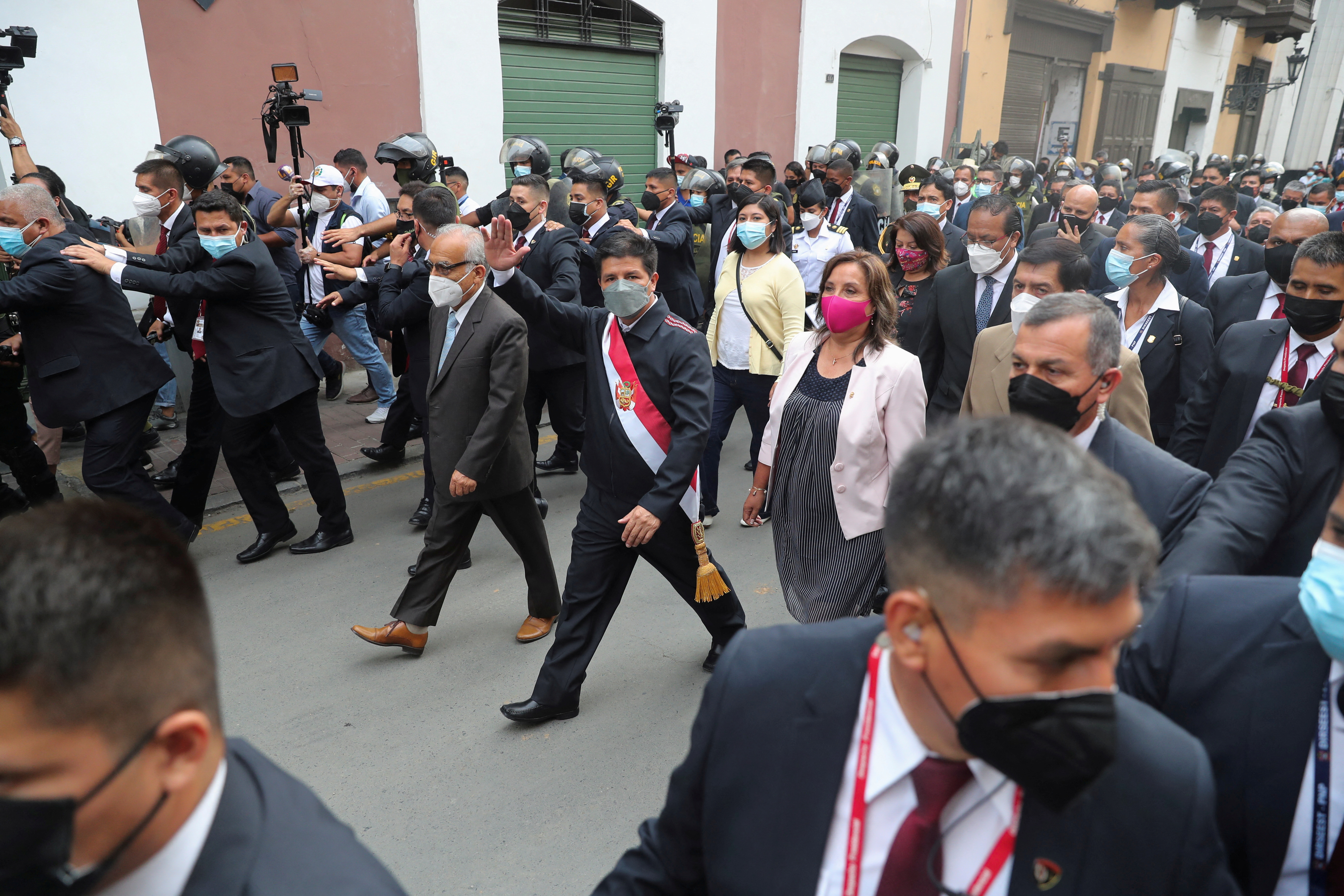 Peru's President Pedro Castillo waves as he walks a day after lawmakers voted to start an impeachment process against him, in Lima