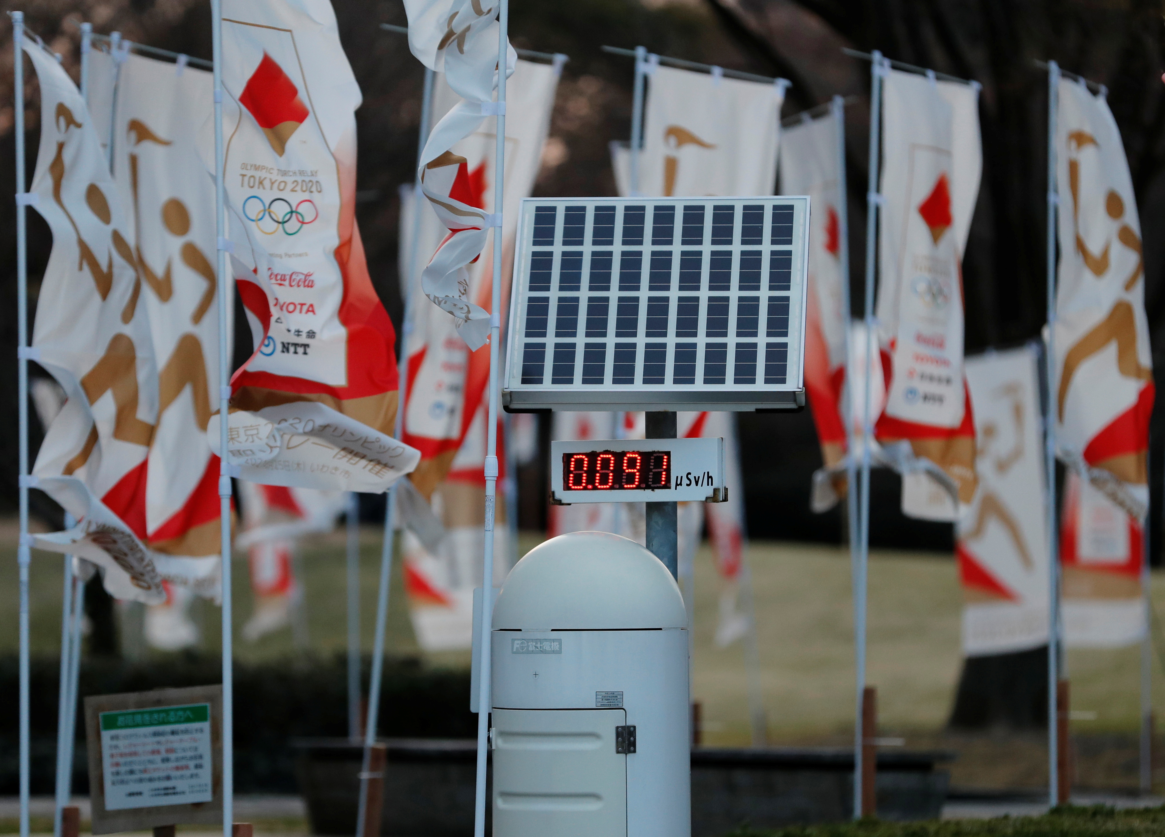 A Geiger counter is seen next to Tokyo 2020 Olympic Games flags at a park in Iwaki