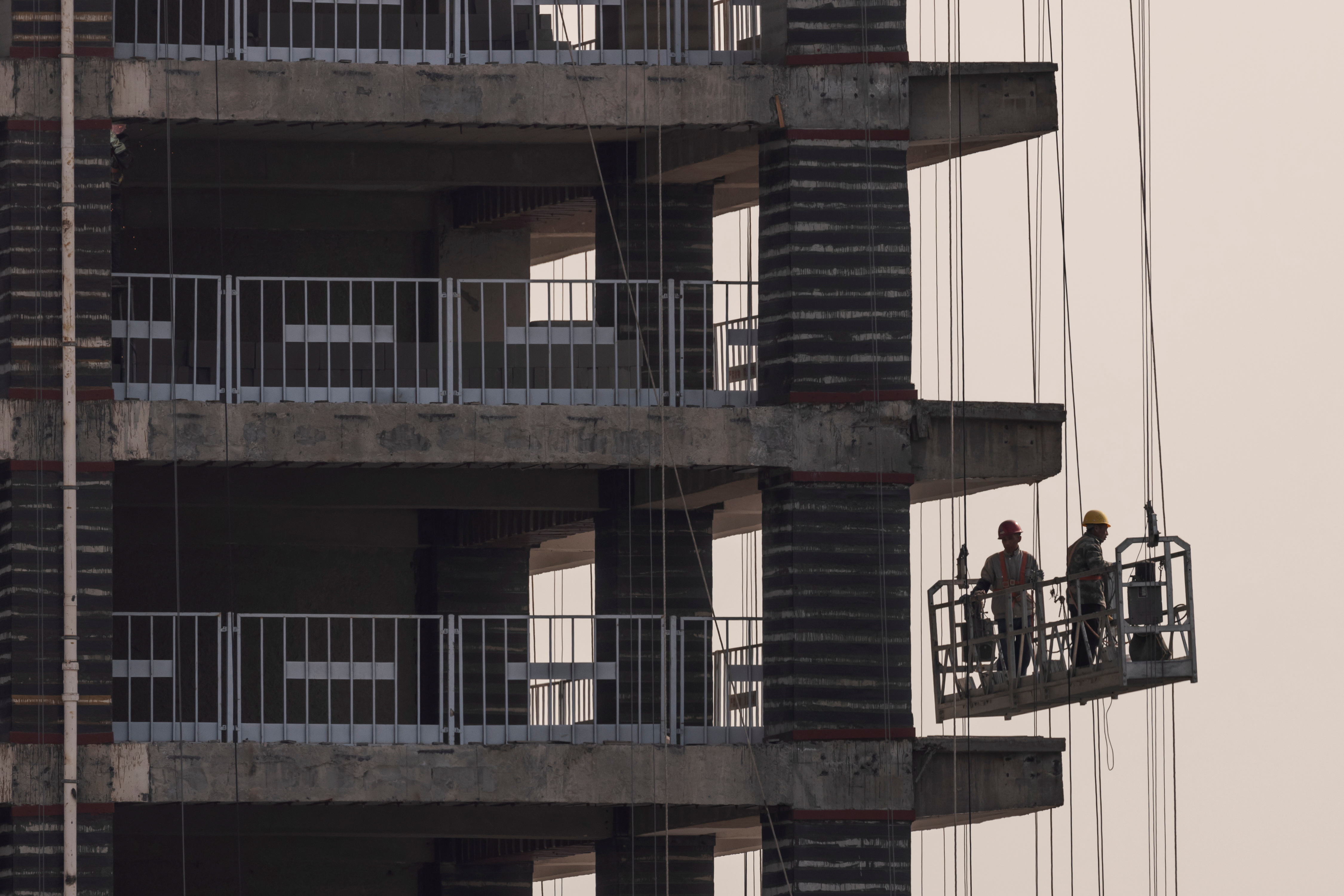 Men work at the construction site of a highrise building in Beijing, China, October 18, 2021.   REUTERS/Thomas Peter