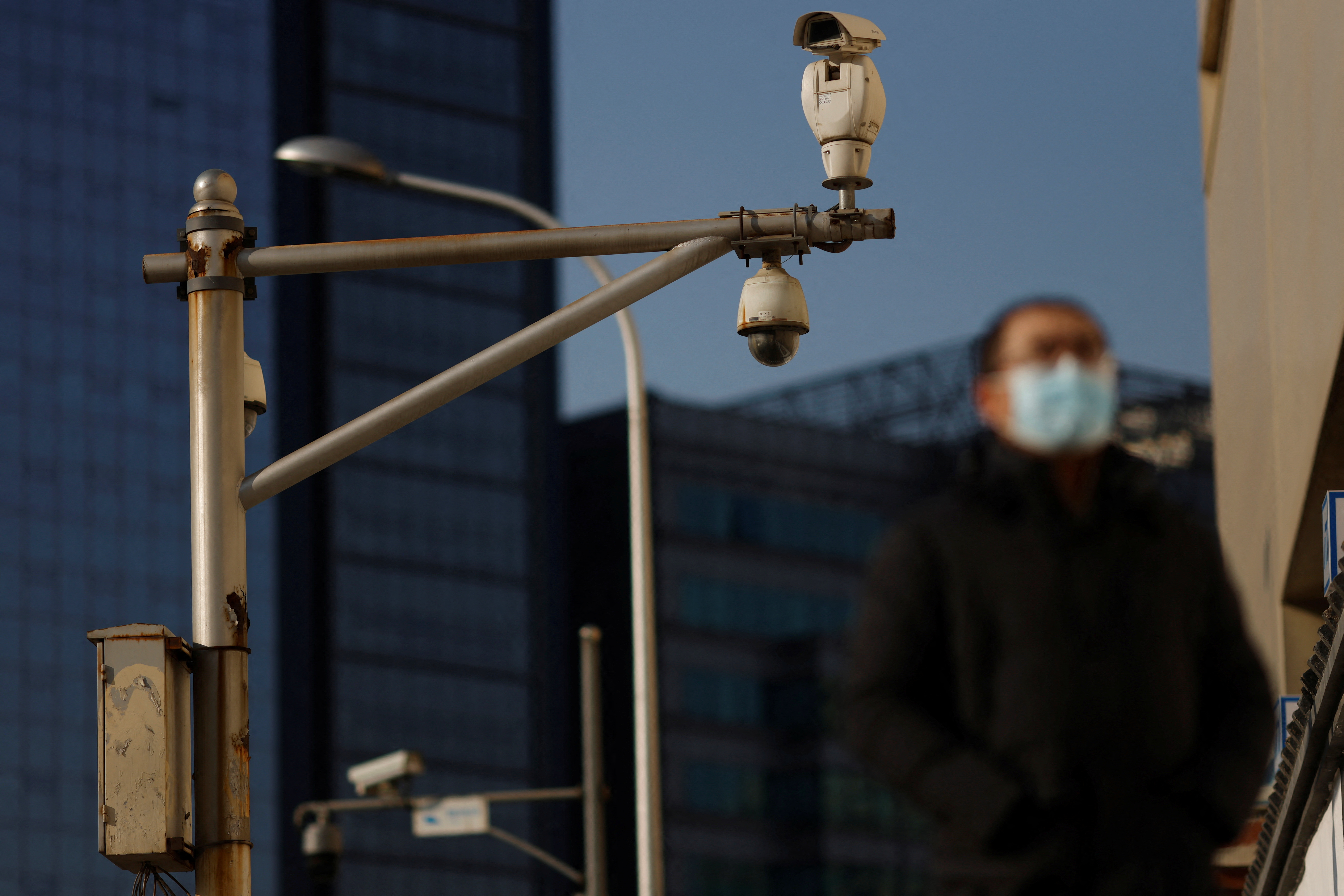 Man walks under surveillance cameras on a street in Beijing