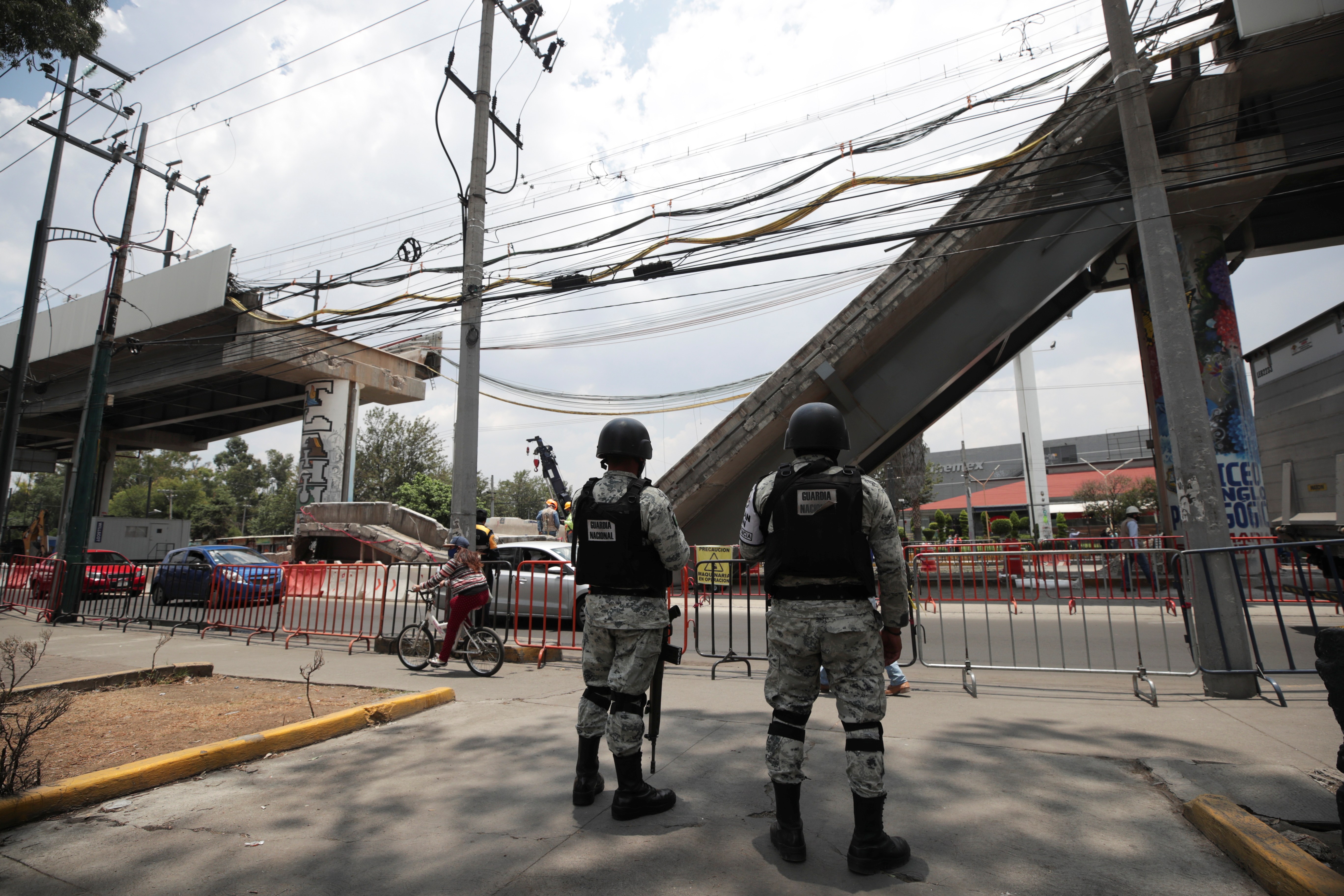 Members of the National Guard stand guard in front of the site where an overpass for a metro partially collapsed with train cars on it, in Mexico City
