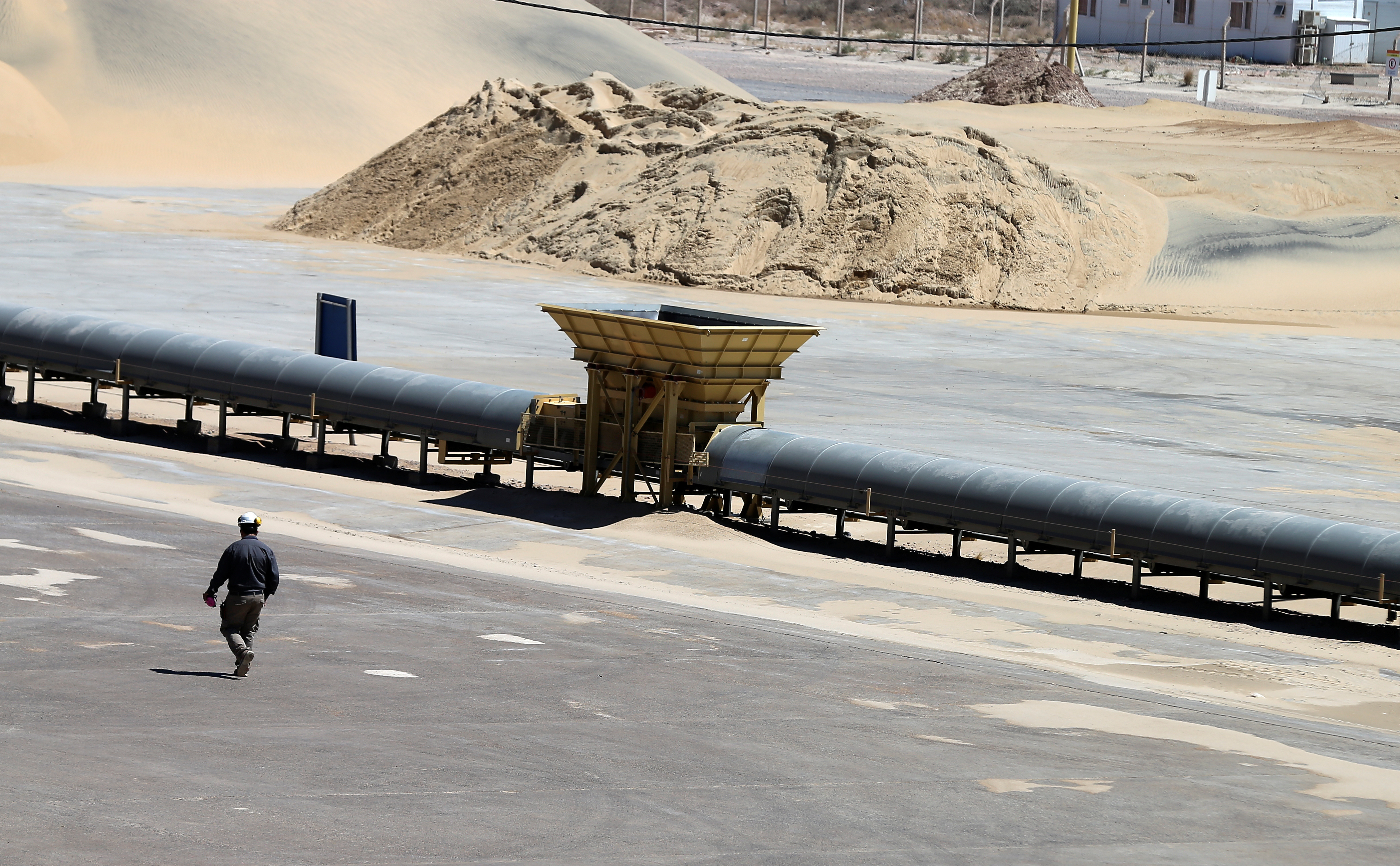 A worker walks near a pile of sand at Vaca Muerta shale oil and gas drilling, in the Patagonian province of Neuquen