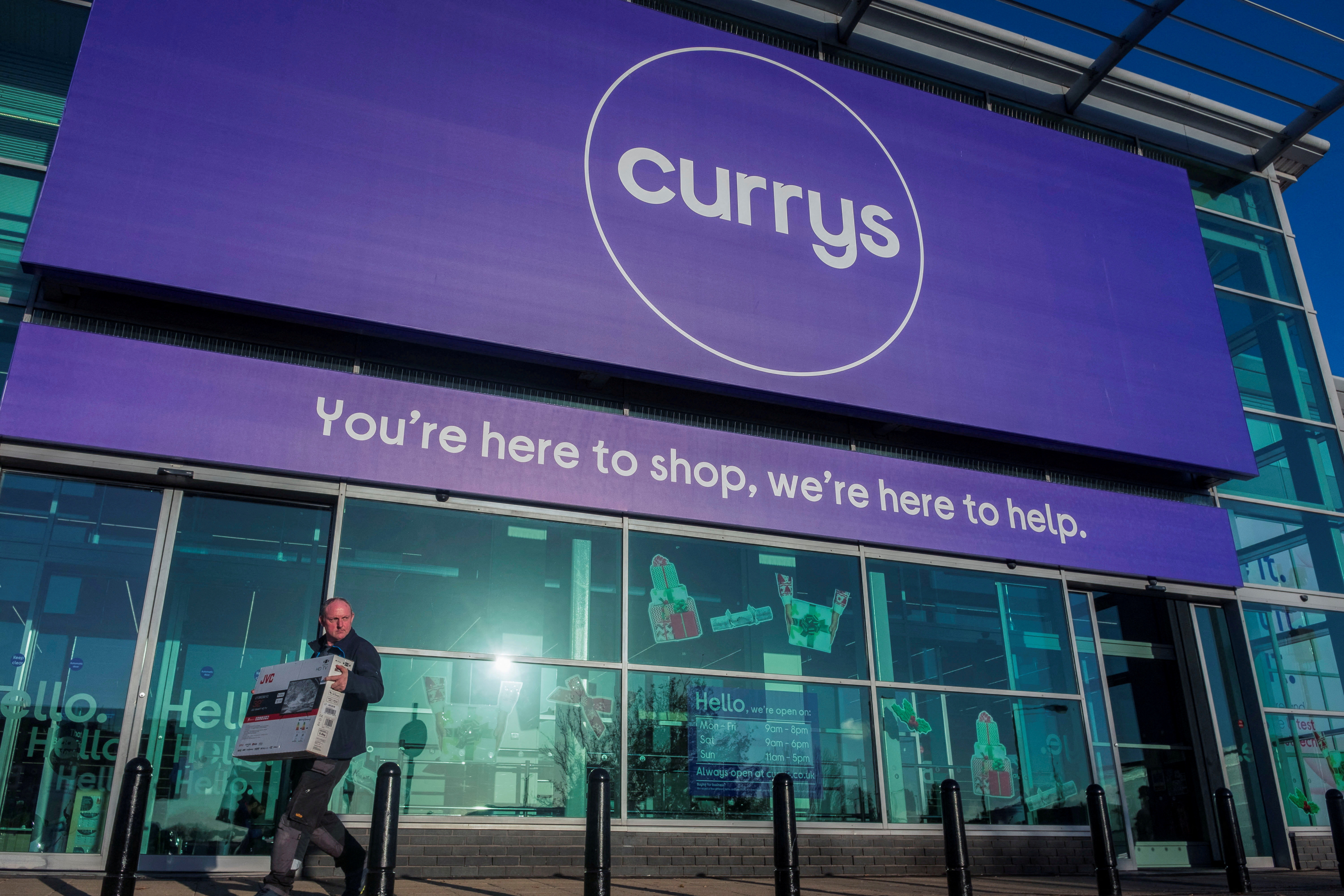 A person carries a television outside a Currys store in London