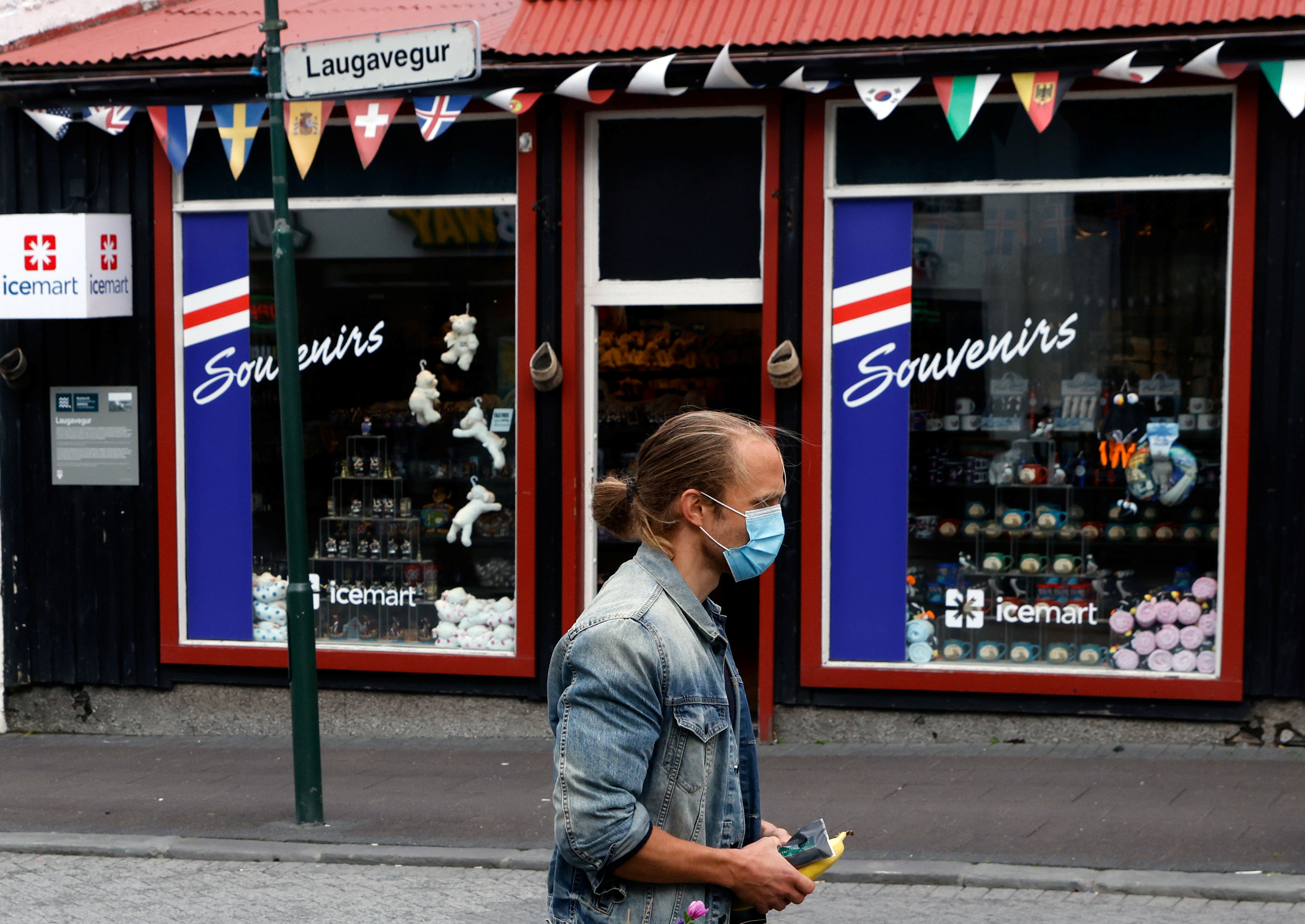 A man with a face mask walks past a tourist shop as the outbreak of the coronavirus disease (COVID-19) continues in Reykjavik