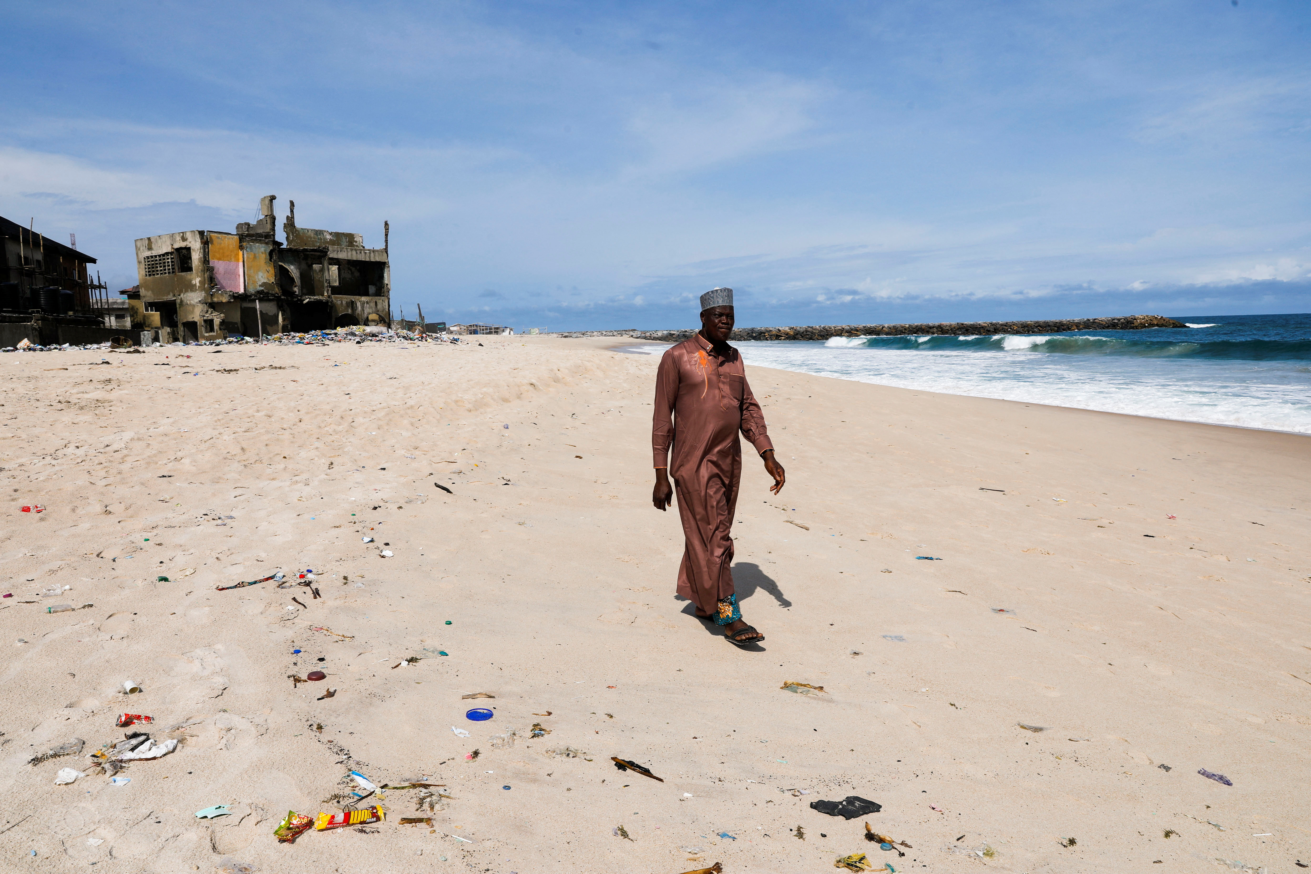 Mureni Alakija, 68, a Nigerian businessman displaced by an ocean surge, walks on the shore of Alpha beach, in Lagos