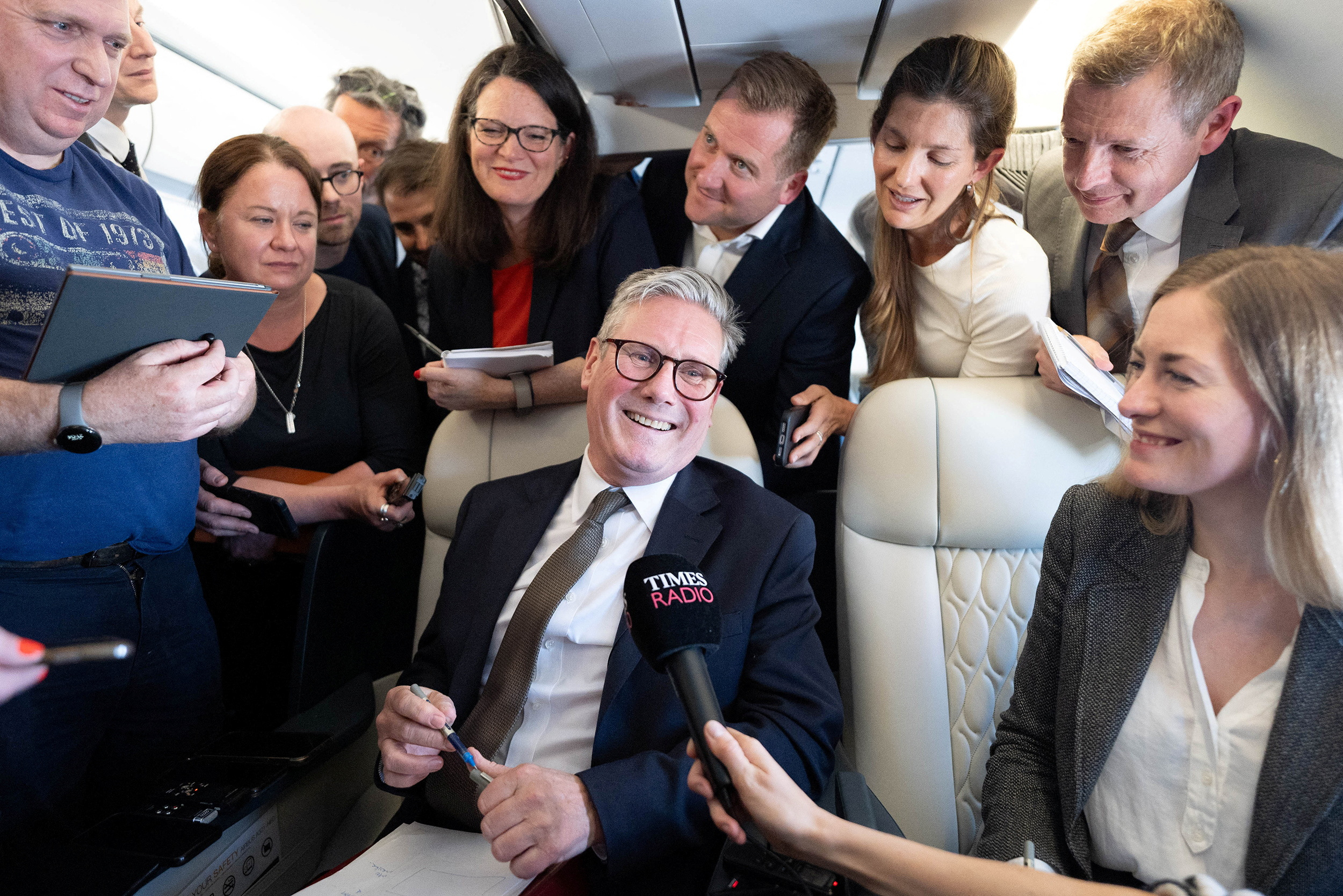Britain's Prime Minister Sir Keir Starmer talks to journalists as he travels onboard a plane to Washington DC