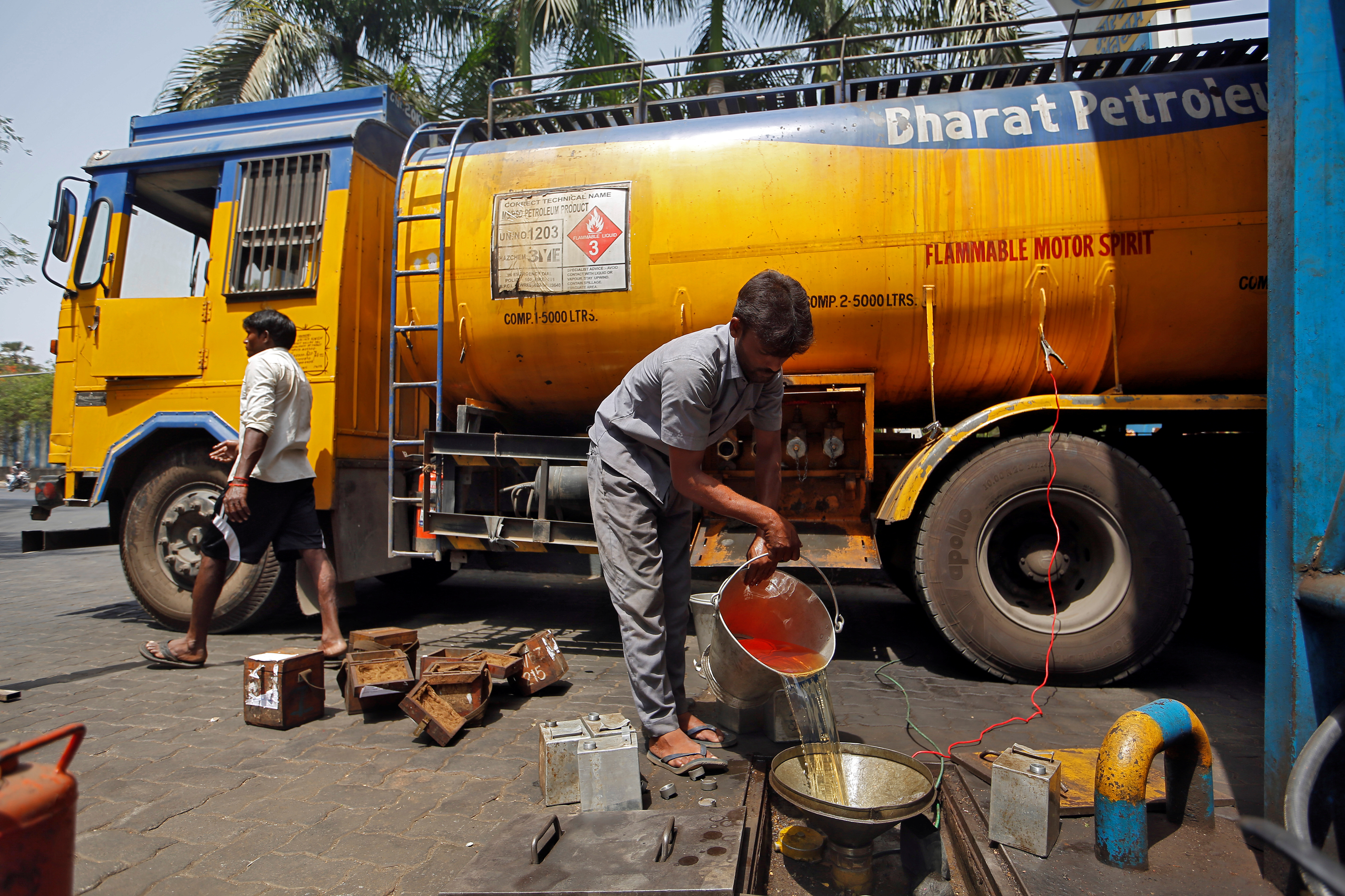 A man pours petrol into an underground tank at a fuel station in Mumbai