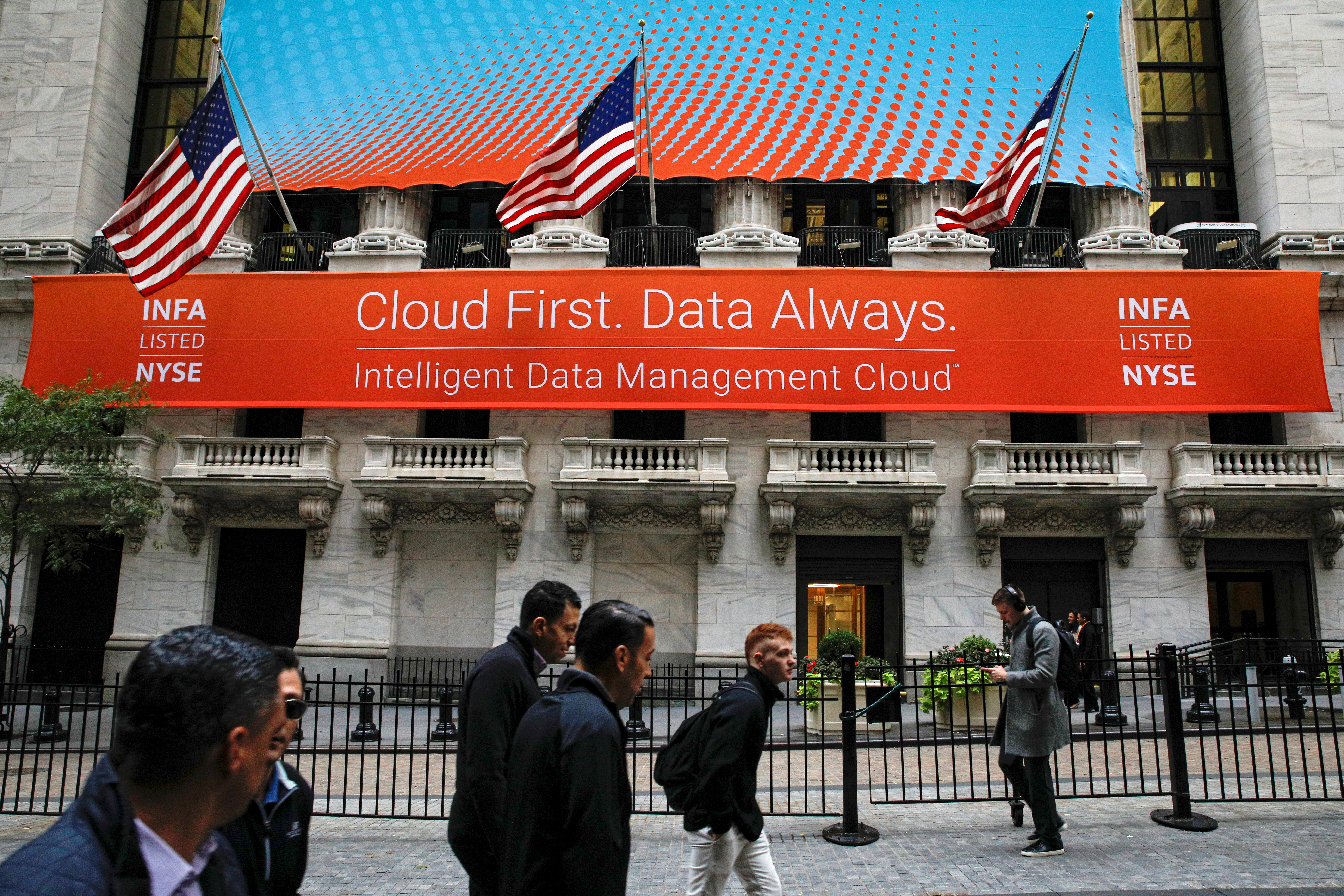 People pass by a banner celebrating the Informatica IPO on the front of the NYSE in New York