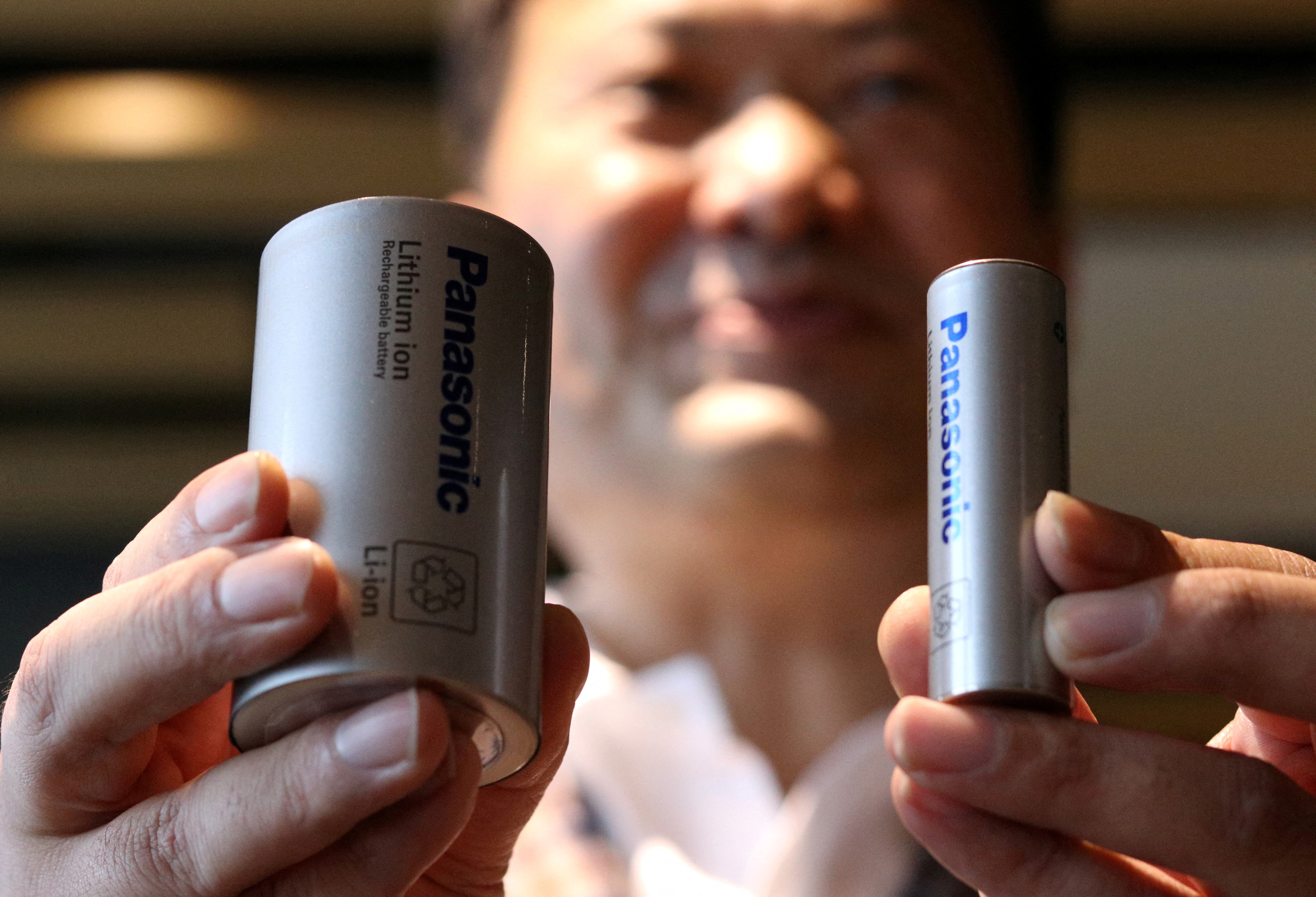 Kazuo Tadanobu, CEO of Panasonic's Energy Company holds a prototype of the 4680 format battery cell (L) next to the current 2170 battery supplied to Tesla Inc during a news conference in Tokyo
