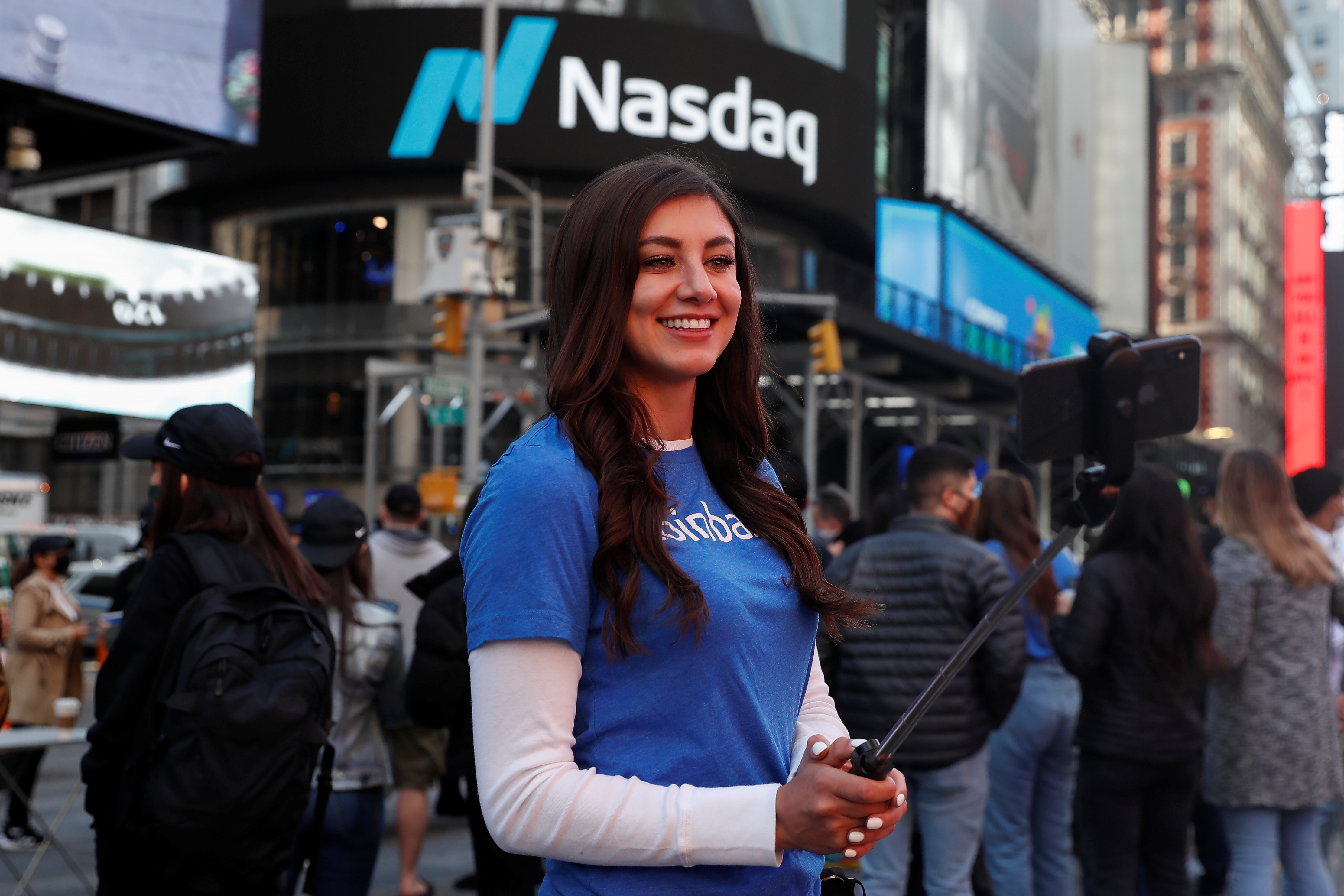 Sandra Robles, an employee of Coinbase, takes a selfie as as Coinbase Global Inc, the biggest U.S. cryptocurrency exchange, is displayed on the Nasdaq MarketSite jumbotron (not pictured) at Times Square in New York