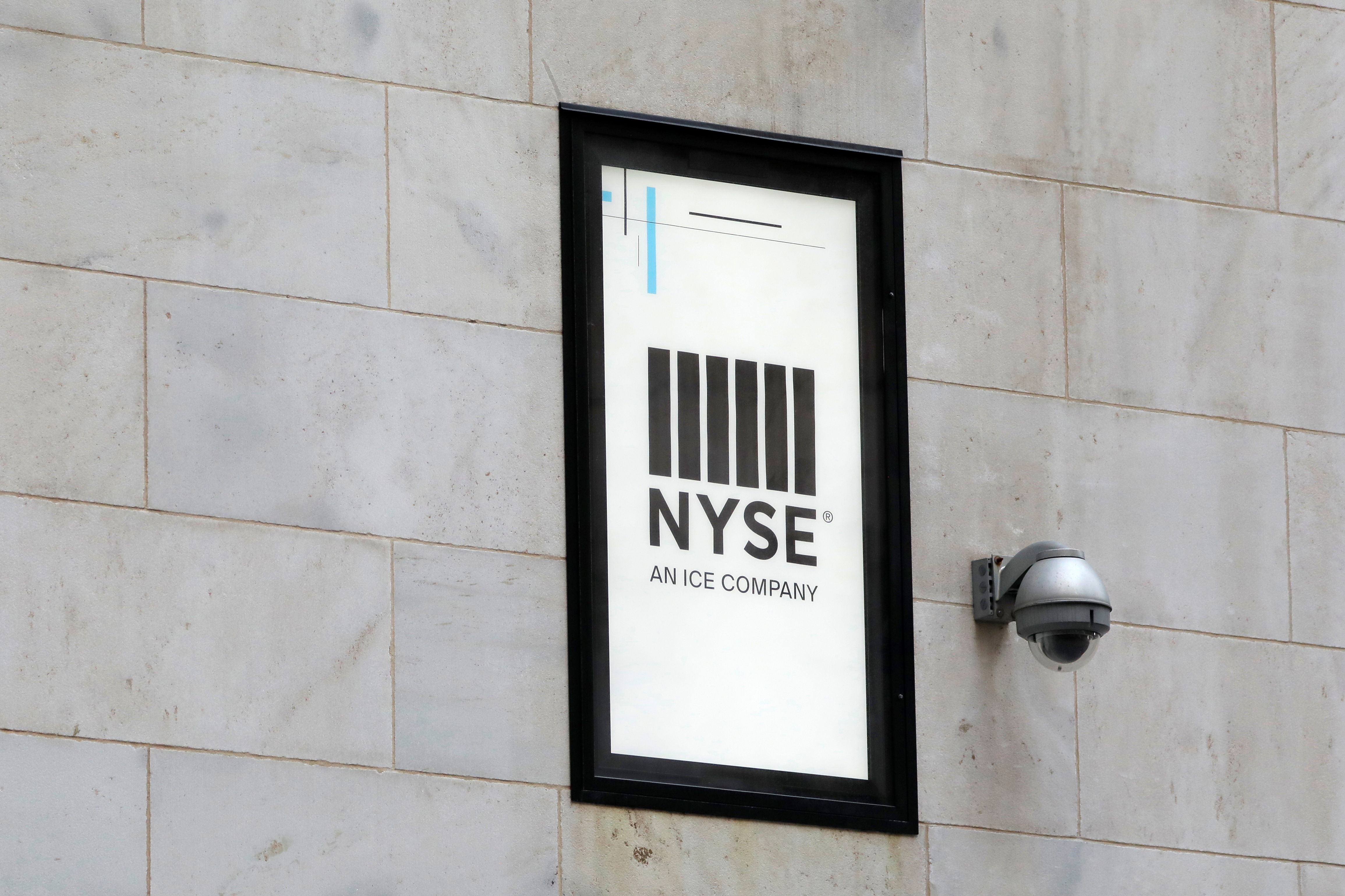 A security camera is seen next to signage outside of the New York Stock Exchange (NYSE) in New York City, New York