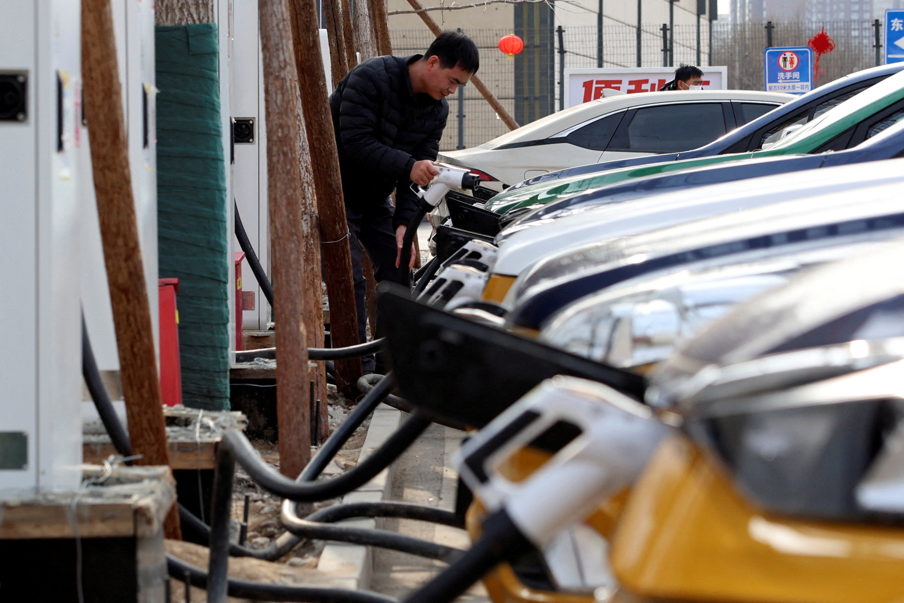 A man charges a car at an EV charging station in Beijing