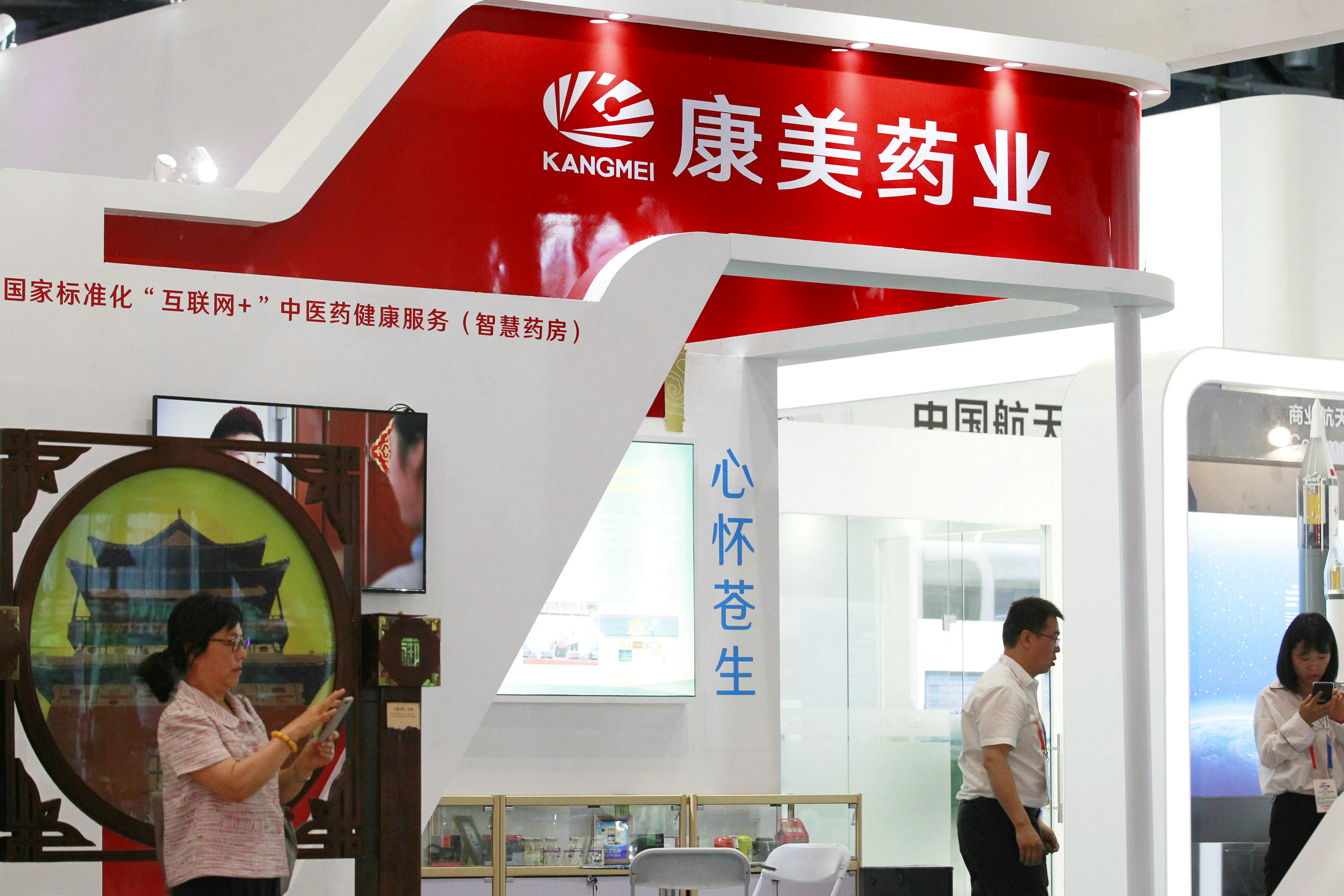 People are seen at the booth of Kangmei Pharmaceutical Co at a trade and service fair in Beijing
