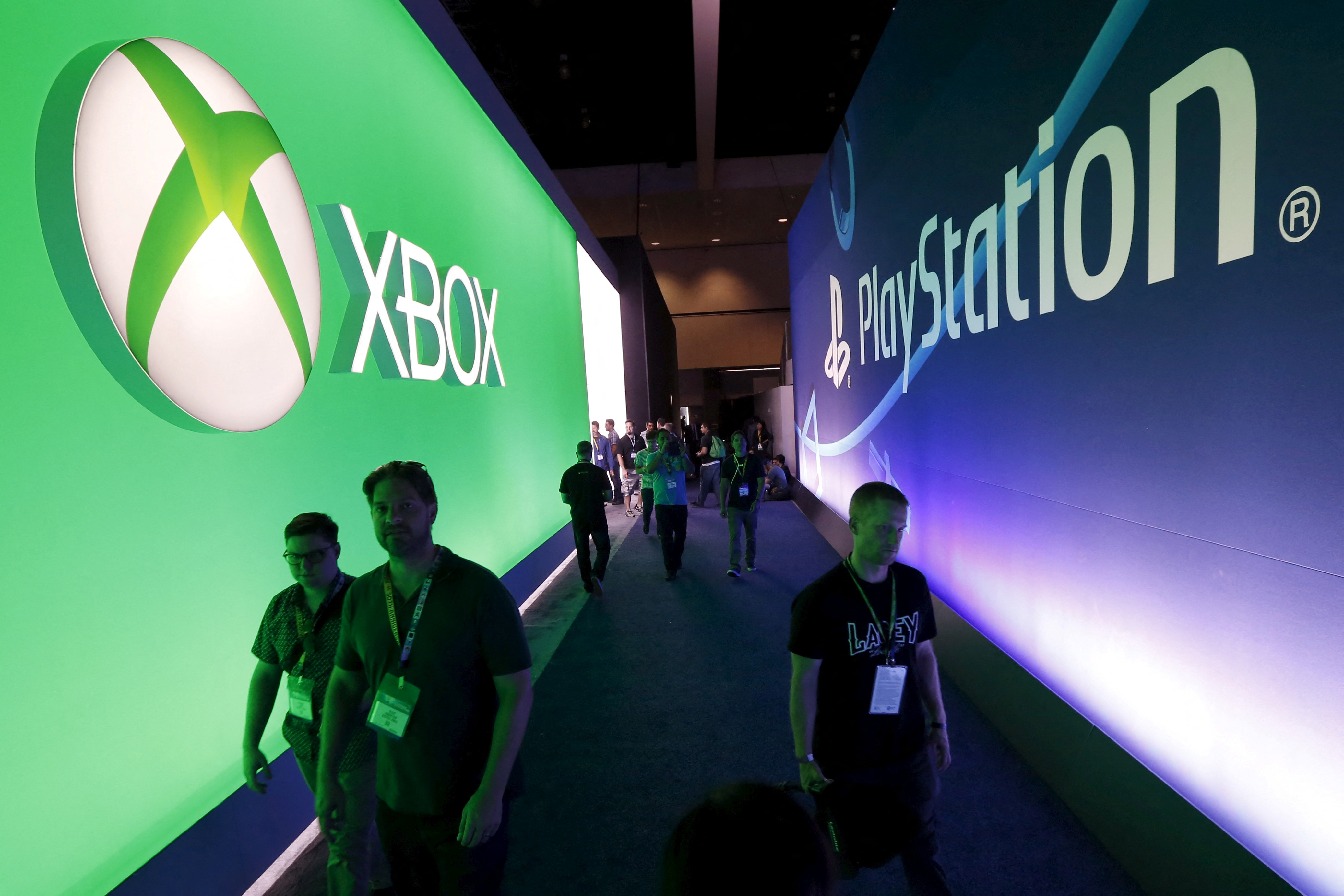 Attendees walk past a Microsoft Xbox sign opposite a Sony PlayStation sign at the Electronic Entertainment Expo, or E3, in Los Angeles