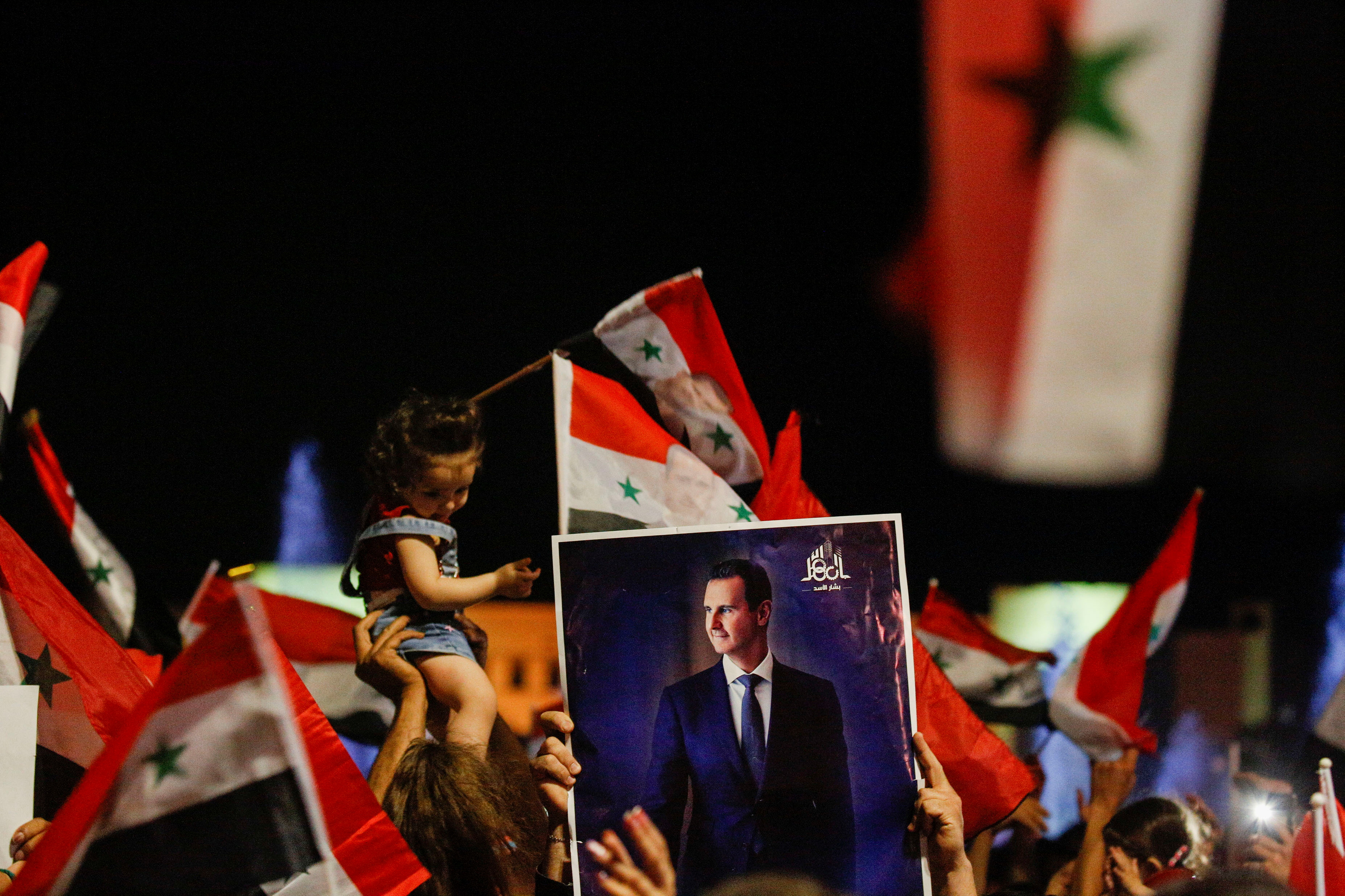 Supporters of Syria's President Bashar al-Assad celebrate before the results of the presidential election in Damascus