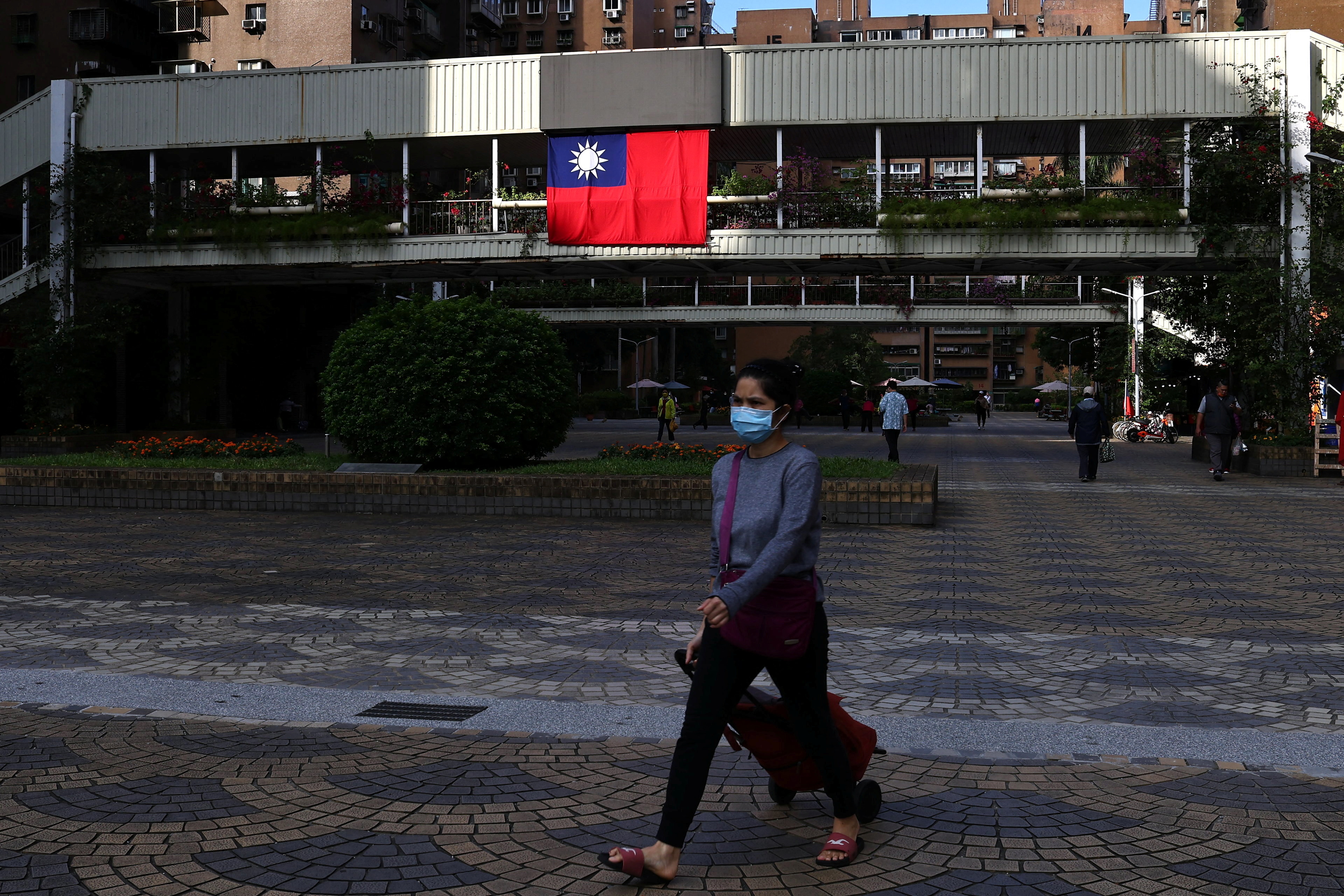 A woman walks past a Taiwan flag in Taipei