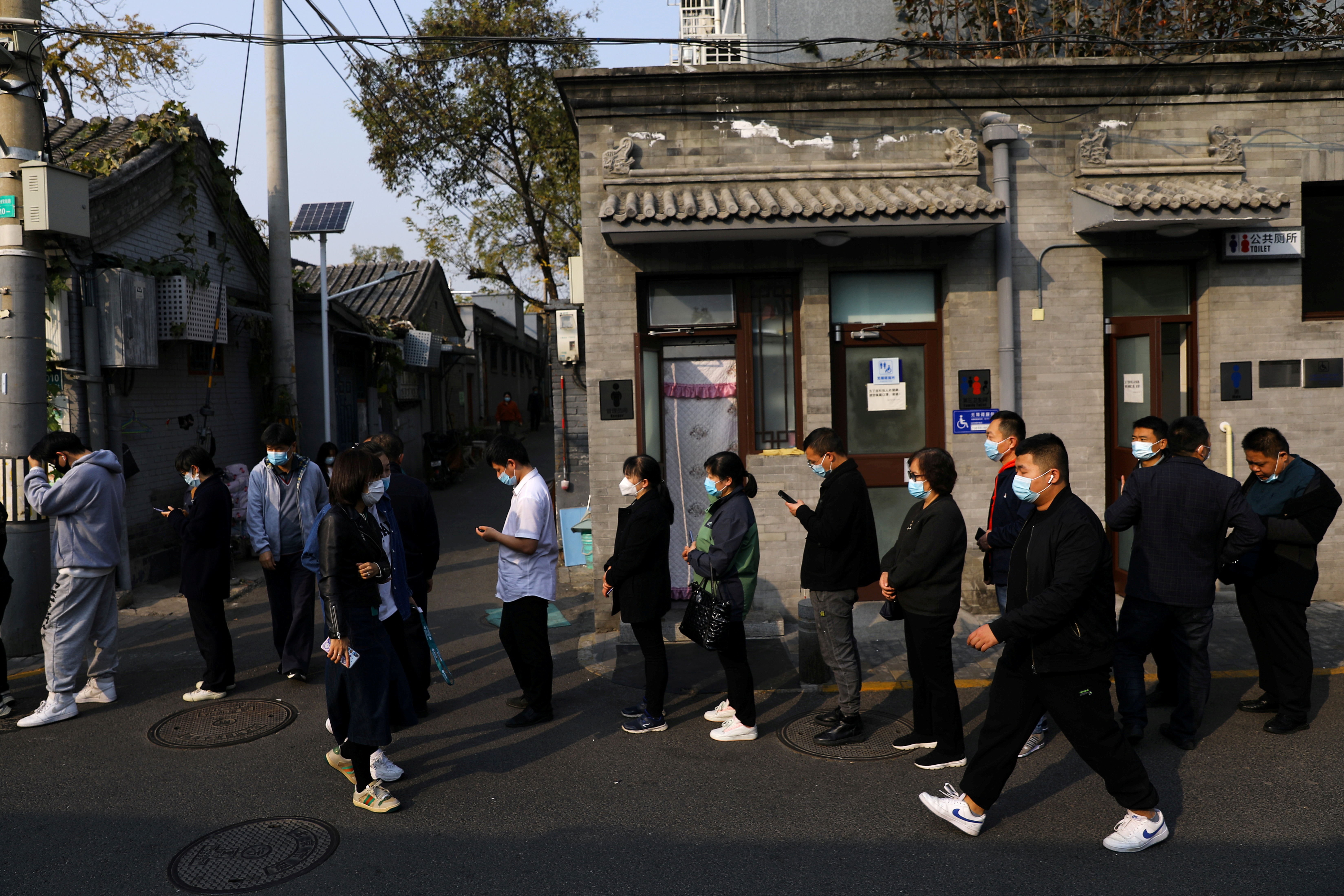People line up outside a vaccination site after the city started offering booster shots of the vaccine against the coronavirus disease (COVID-19) to vaccinated residents, in Beijing, China October 29, 2021. REUTERS/Tingshu Wang/File Photo