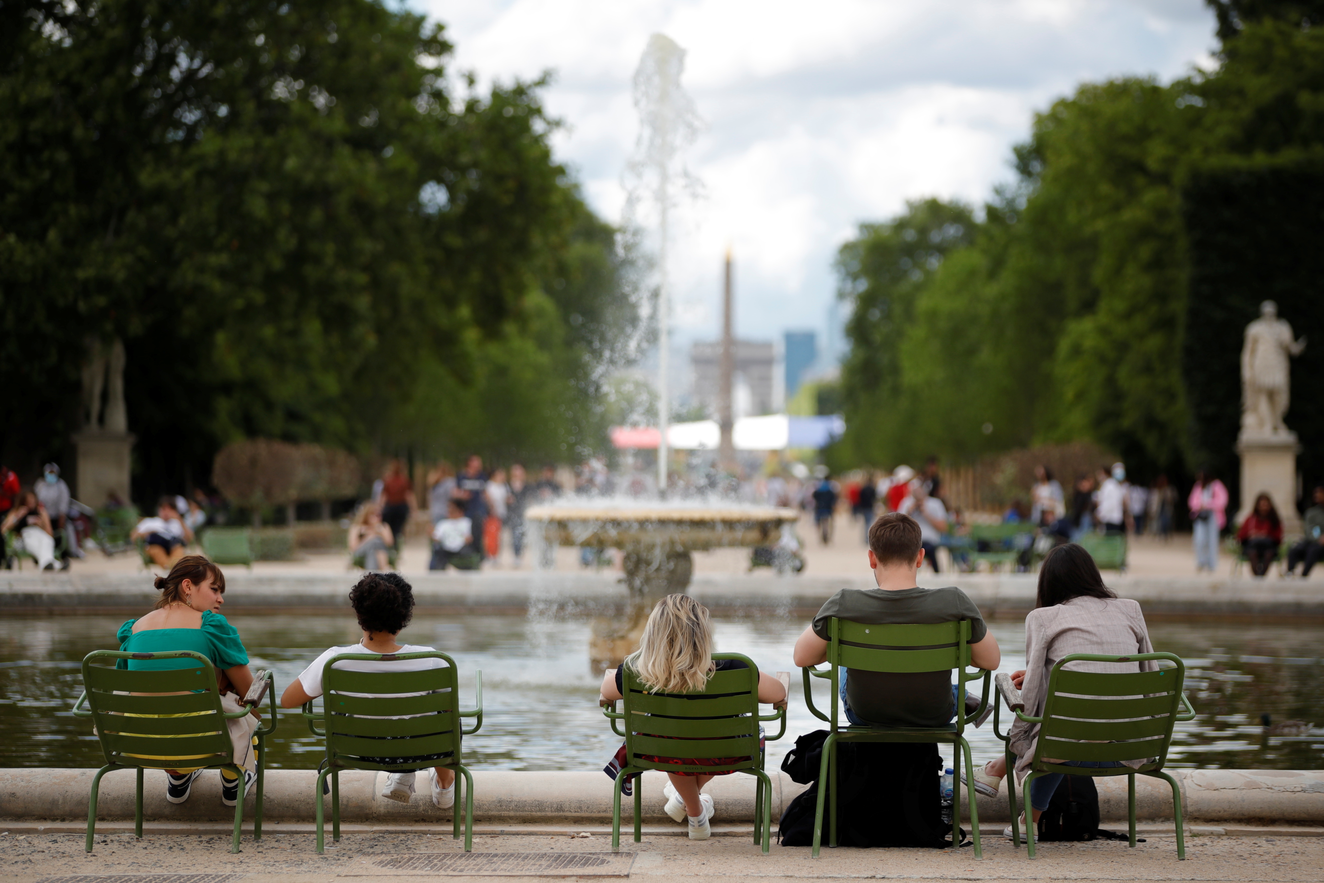 People relax in chairs around a fountain in the Tuileries Garden in Paris