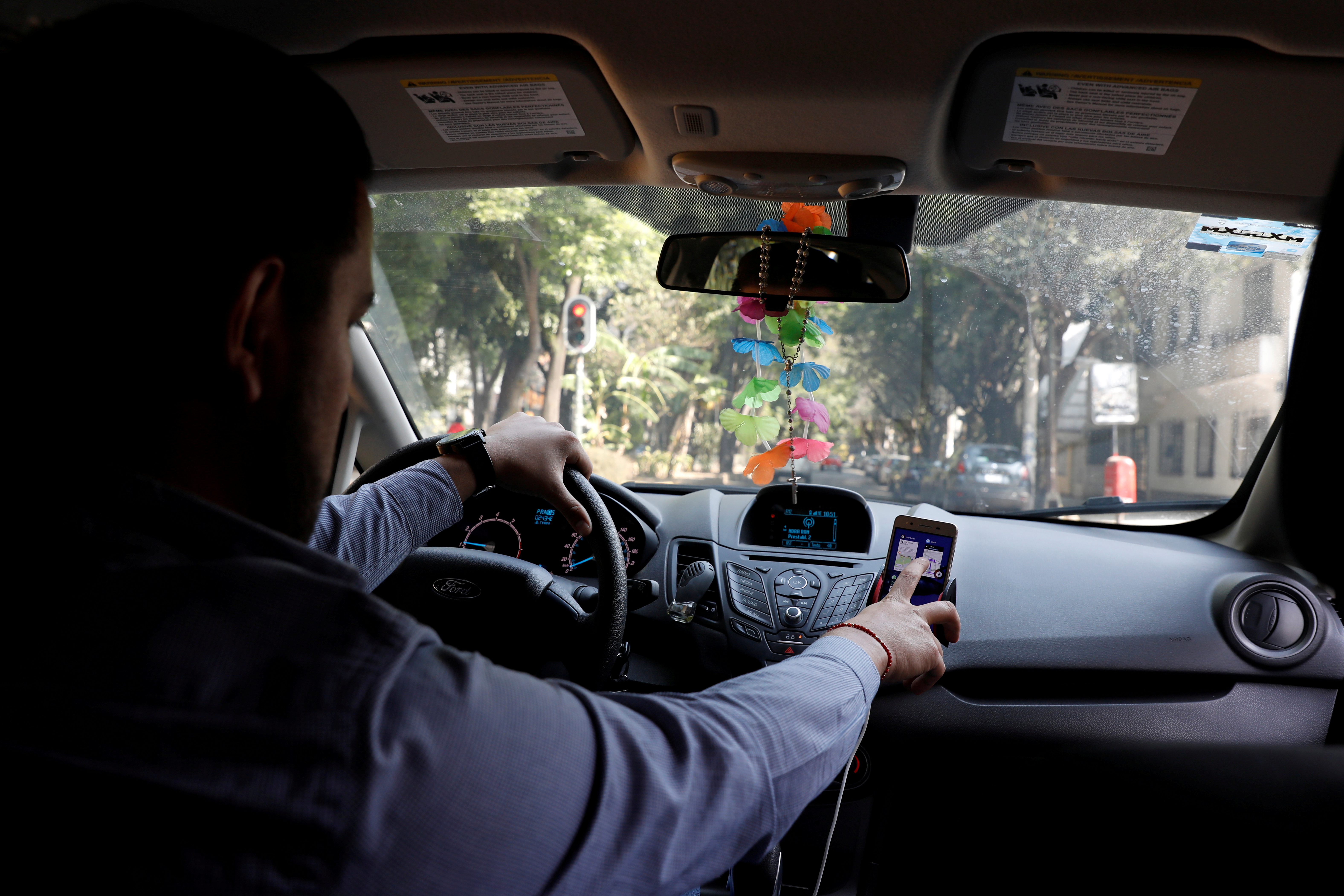 Uber driver checks the route on a mobile phone inside his car in Mexico City