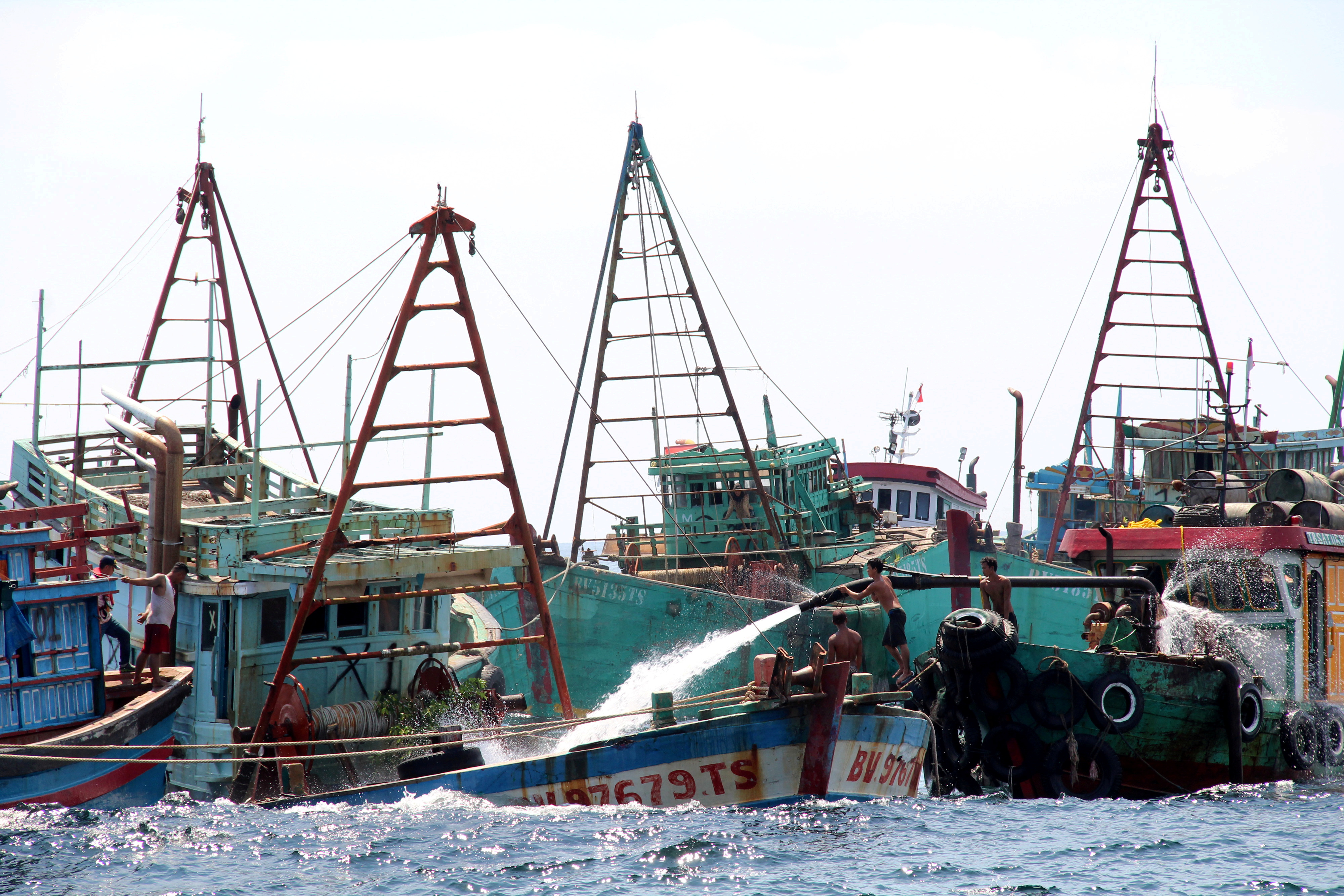 Workers fill Vietnamese fishing boats with water to sink them after they were seized due to illegal fishing in Indonesia's waters, at Datuk island in West Kalimantan