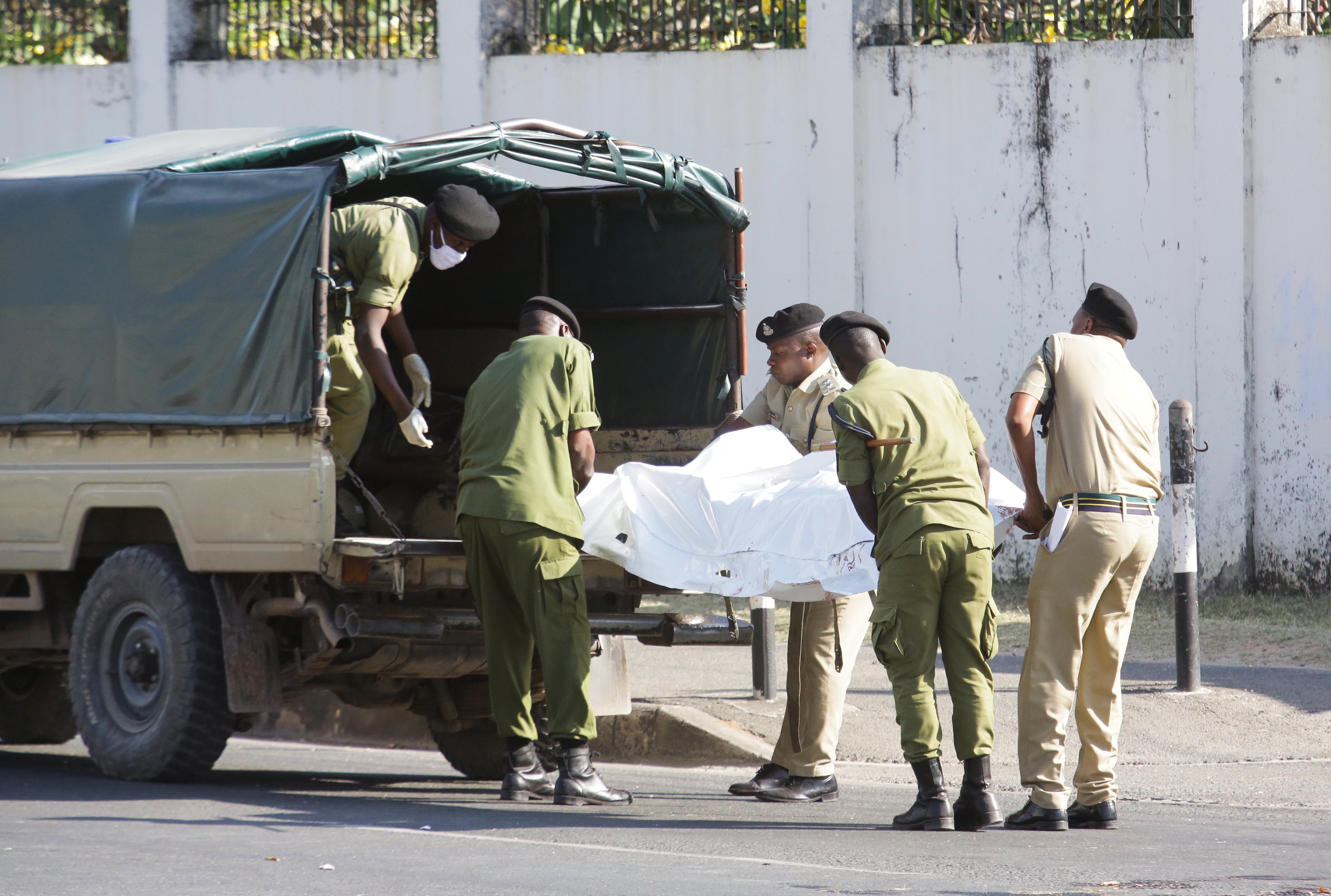 Tanzanian security forces remove the slain body of an attacker who was wielding an assault rifle, outside the French embassy in the Salenda area of Dar es Salaam