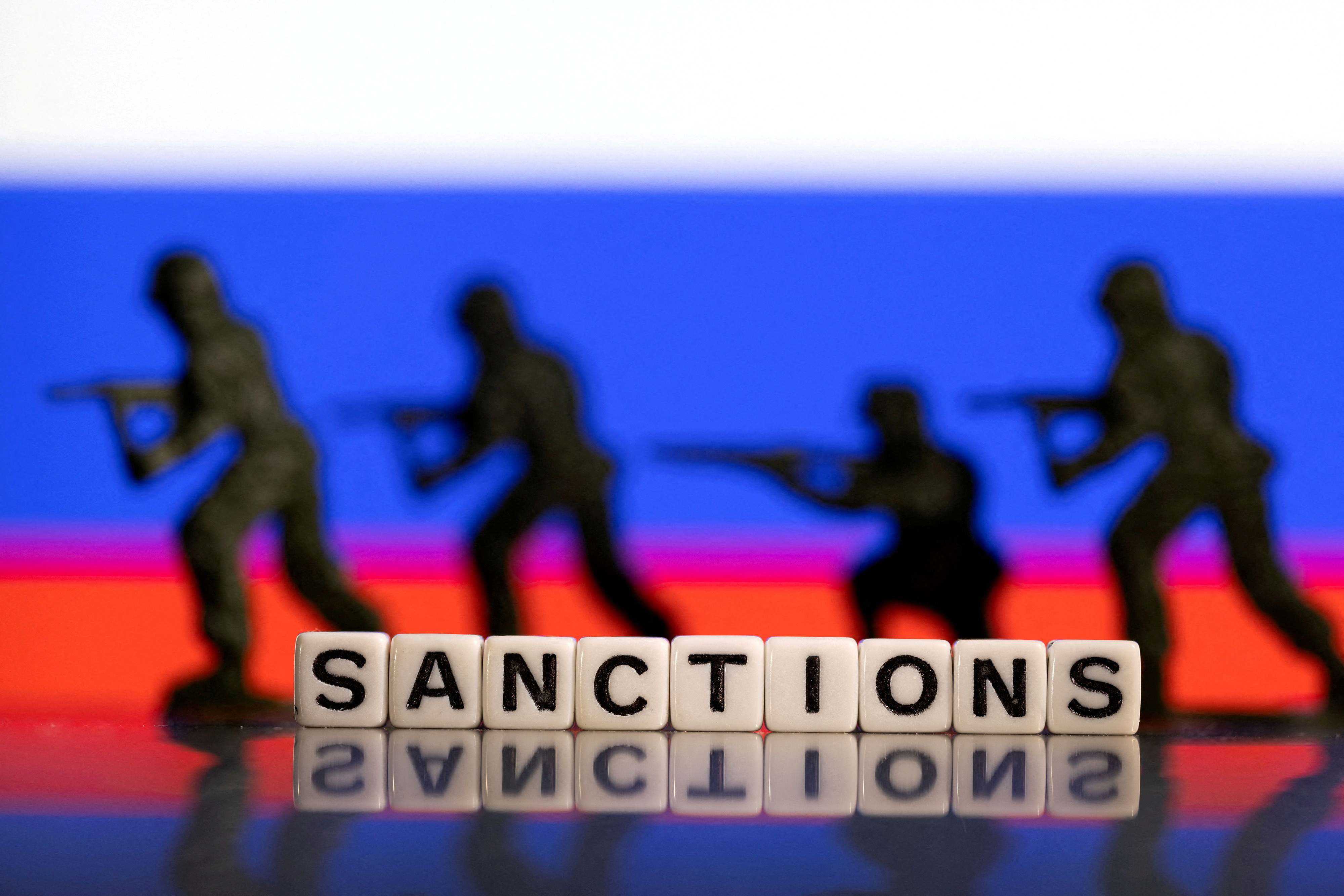 Illustration shows plastic letters arranged to read "Sanctions" and solider toys are placed in front of Russia's flag colors
