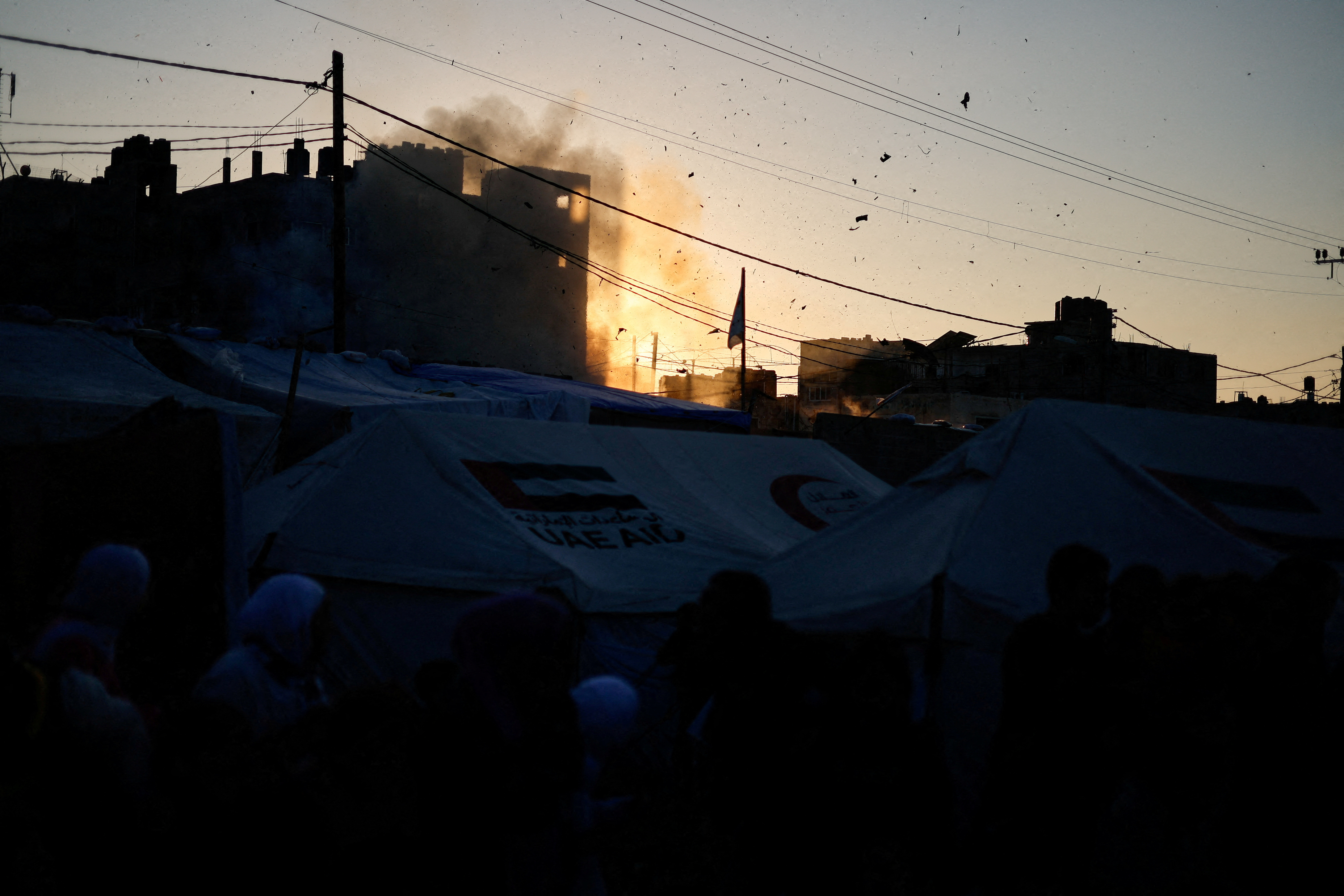 Displaced Palestinians react near their tents following an Israeli strike on a car in Rafah