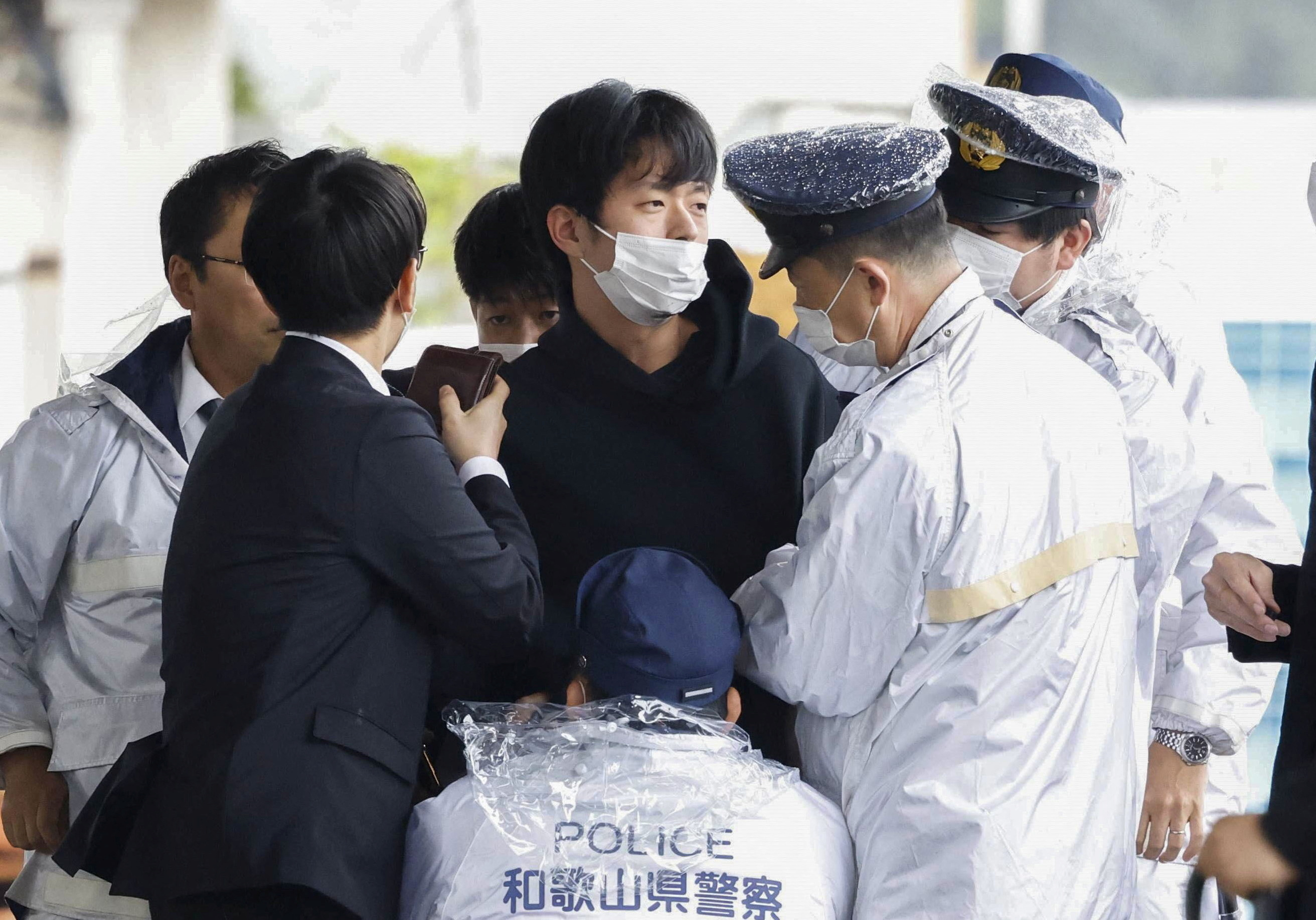 A man, believed to be a suspect who threw a pipe-like object near Japanese Prime Minister Fumio Kishida during his outdoor speech, is held by police officers in Wakayama