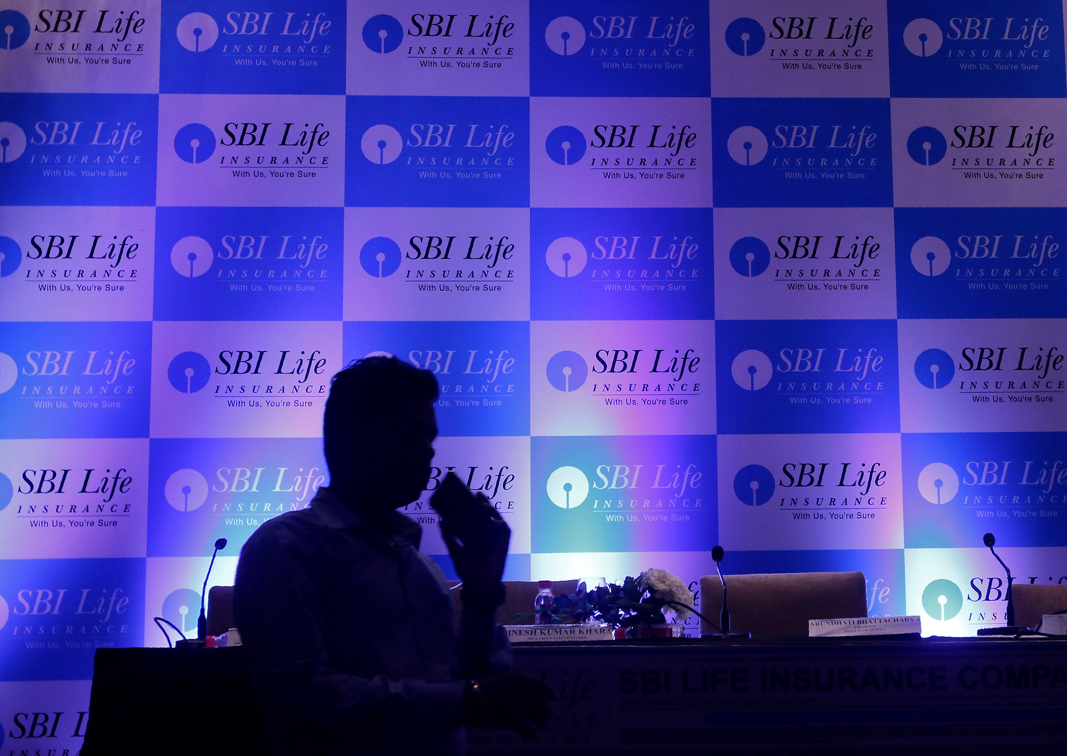 A man walks past a podium set up at the venue of a news conference to announce the launch of Initial Public Offering by SBI Life Insurance Co in Mumbai