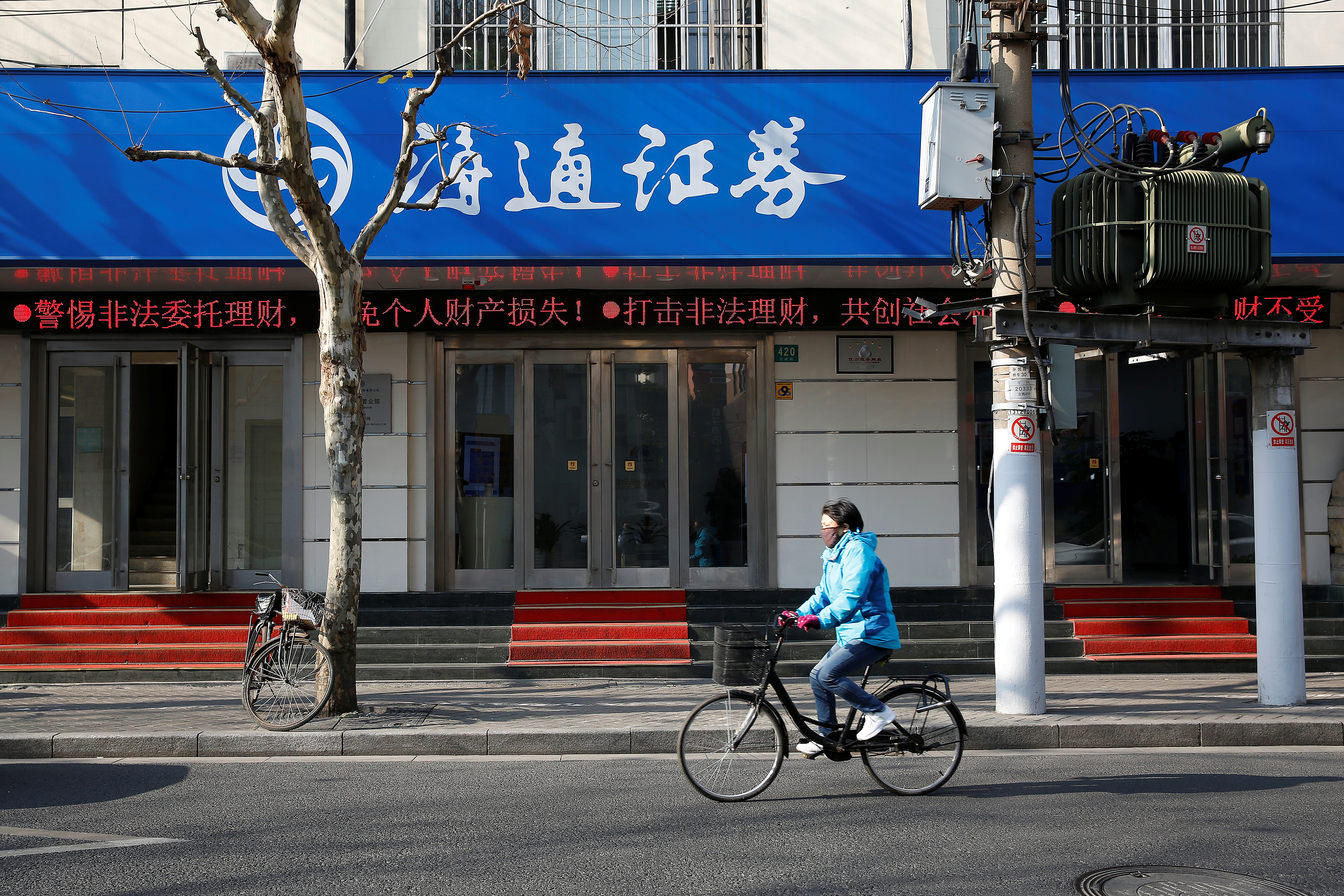 A cyclist rides past a branch of Haitong Securities, in Shanghai