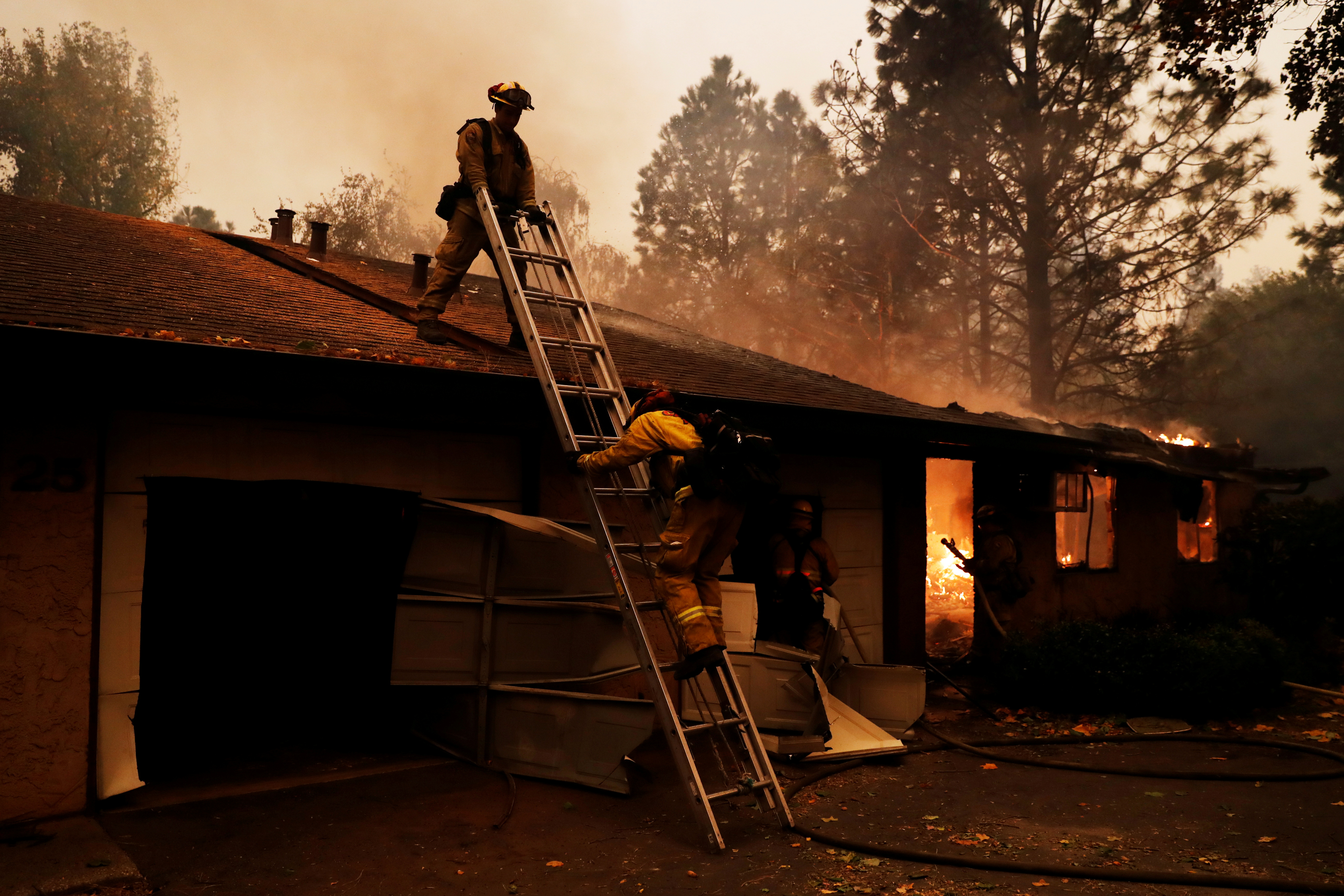 A firefighter climbs a ladder by a burning structure while battling the Camp Fire in Paradise, California, U.S., November 9, 2018. REUTERS/Stephen Lam