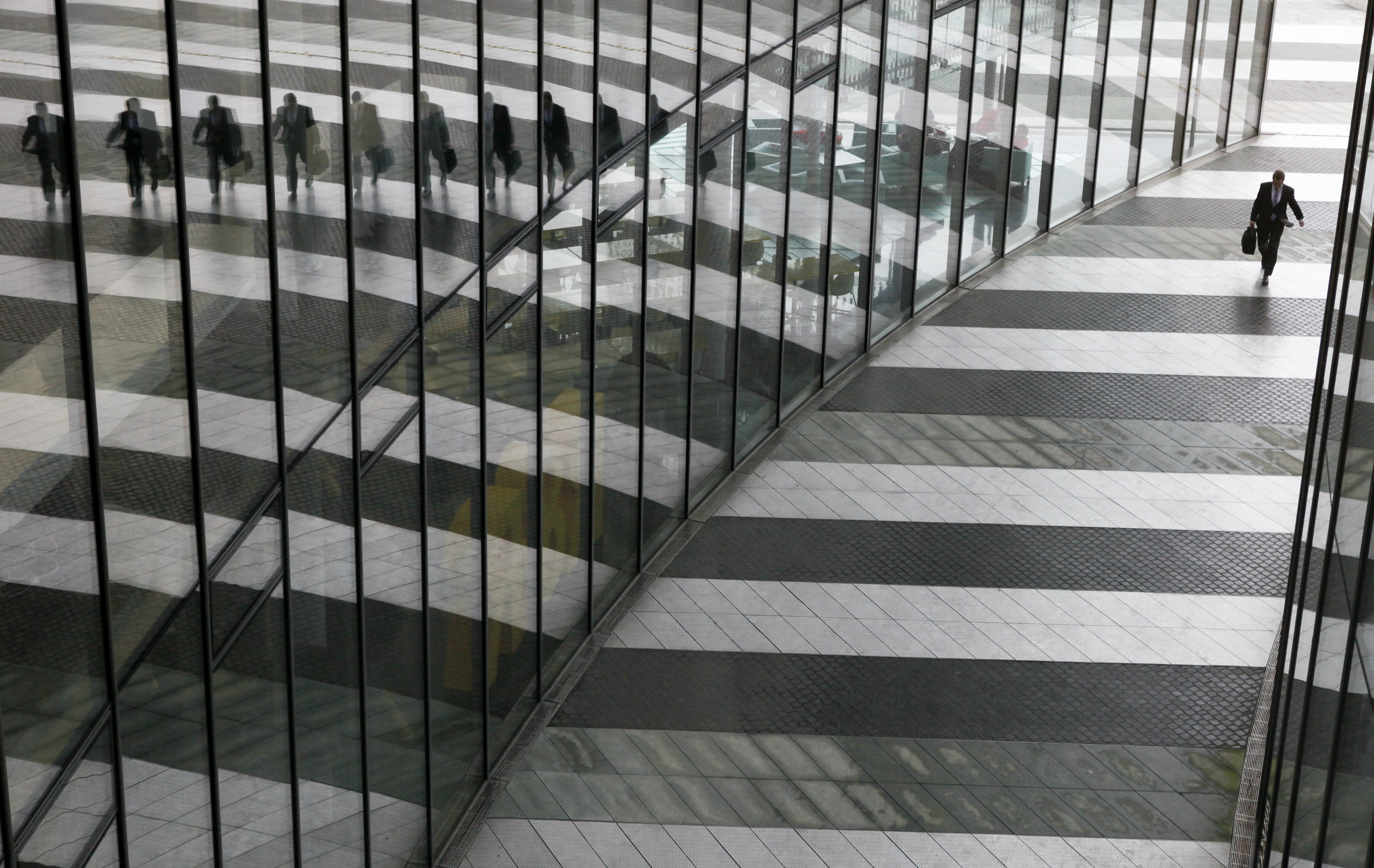 A man is reflected on the glass facade of the Bonn Post Tower in Bonn