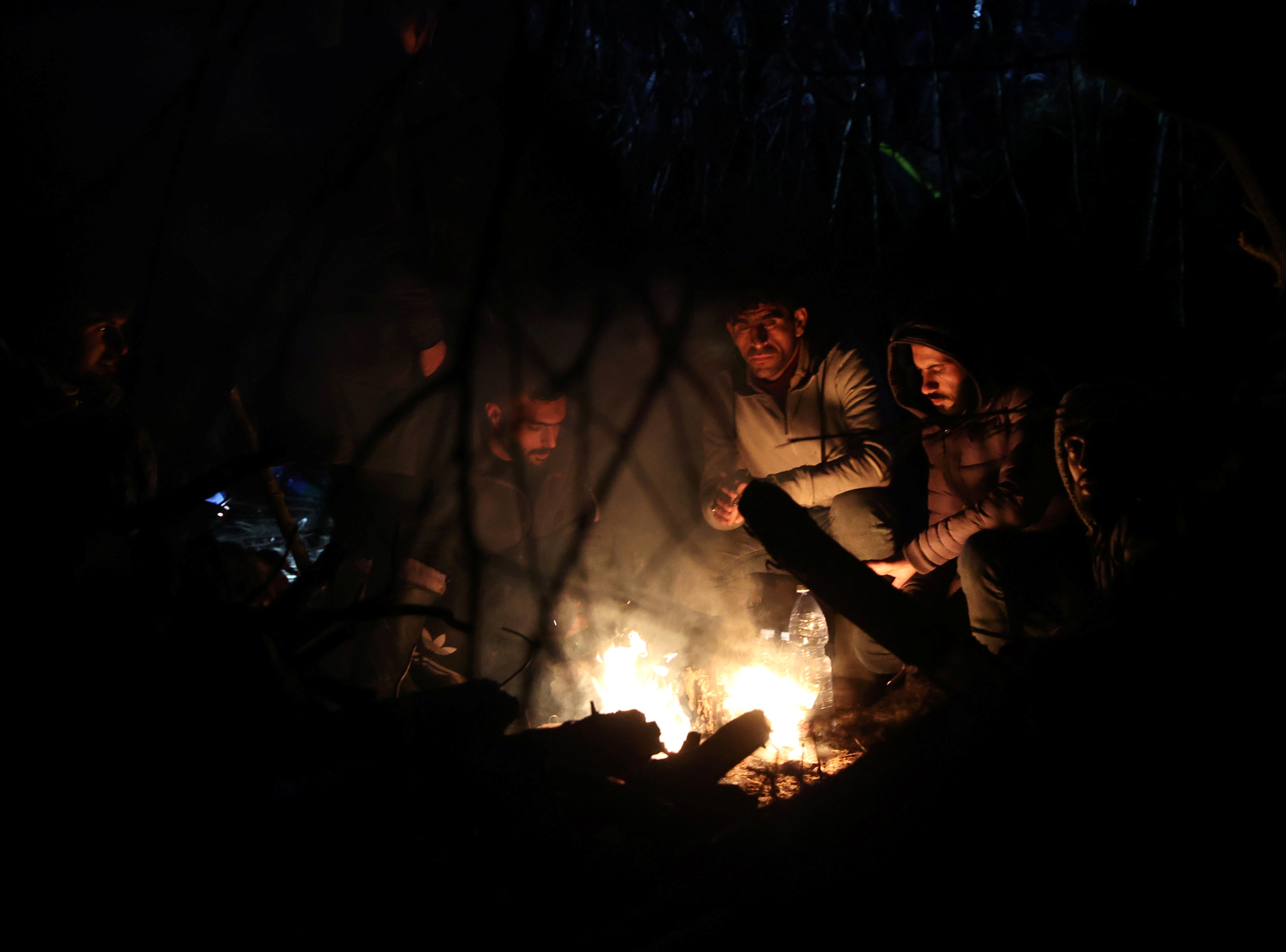 Migrantes reúnense preto dun incendio na fronteira bielorrusa-polaca na rexión de Grodno, Bielorrusia, o 10 de novembro de 2021. Foto tomada o 10 de novembro de 2021. Ramil Nasibulin/BelTA/Handout vía REUTERS