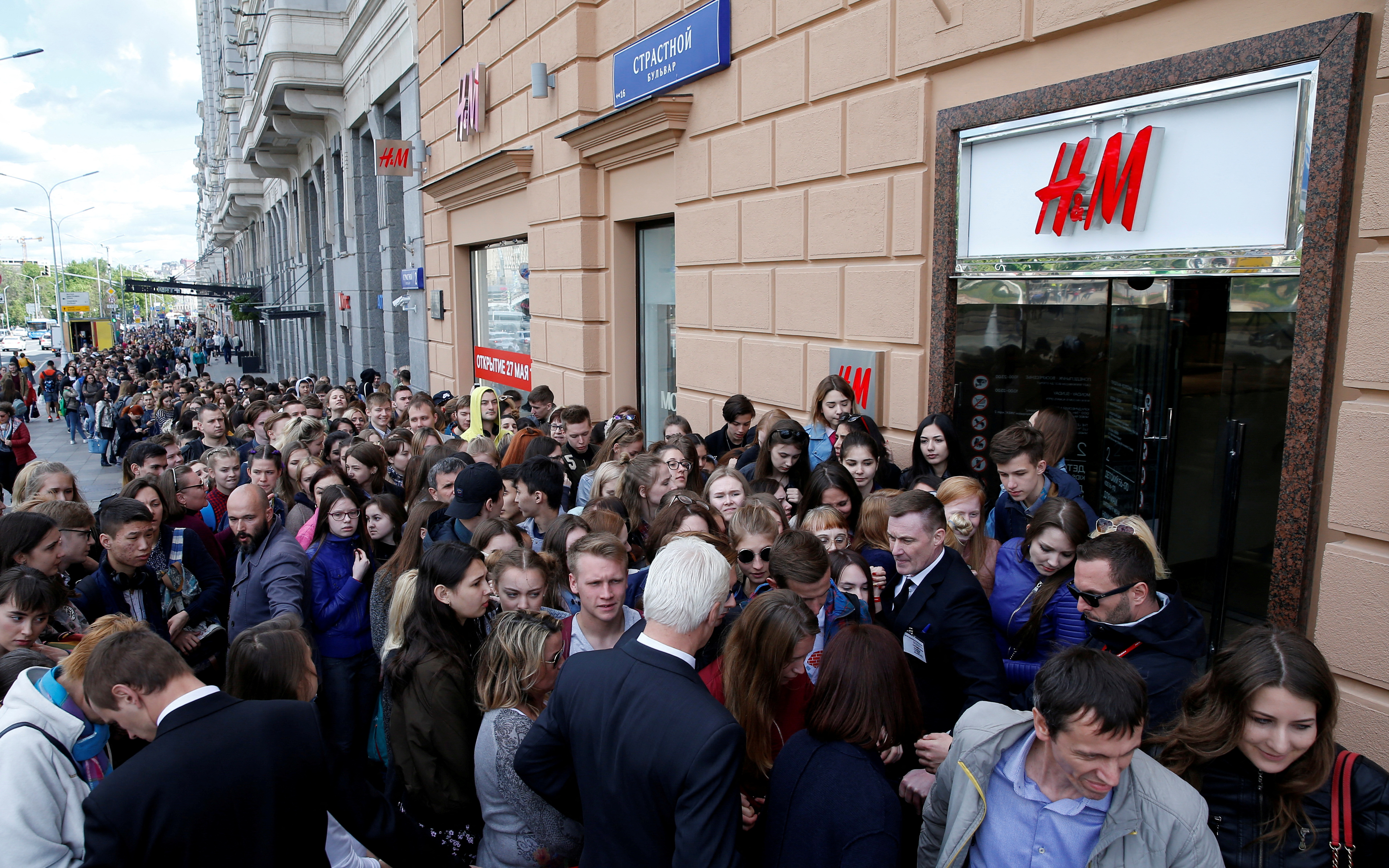 People queue outside the Swedish fashion retailer H&M store on its opening day in central Moscow